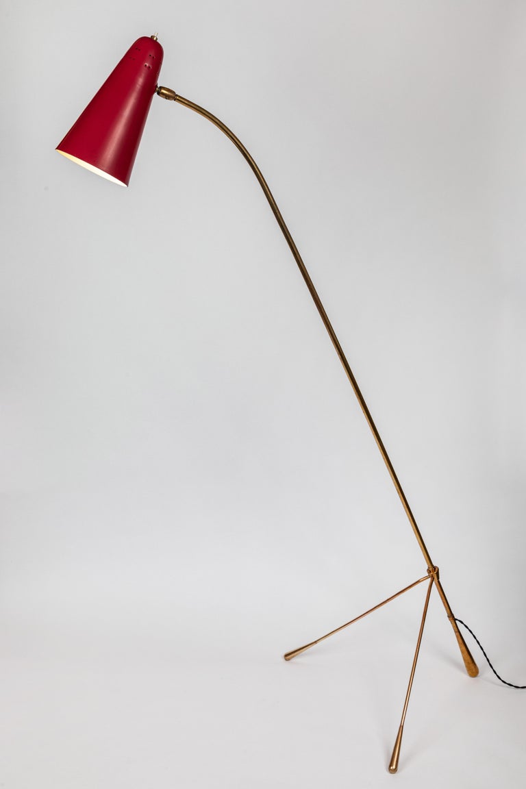 Large 1950s Gilardi & Barzaghi adjustable floor lamp. A rare example executed in red enameled metal perforated shade with a sculptural brass bass. Both the shade and the legs are adjustable, allowing the lamp to be configured in a flexible array of