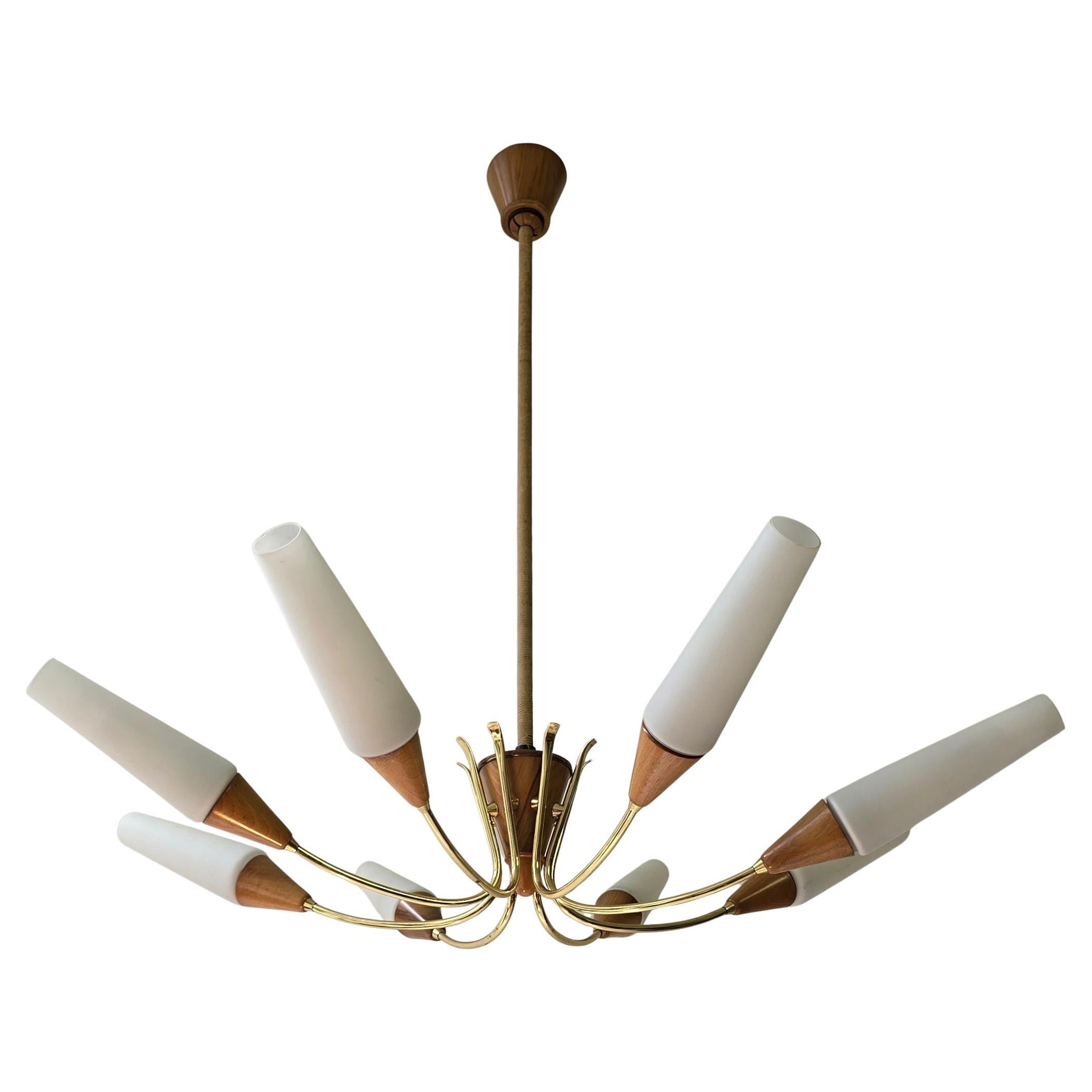 Italian chandelier from the 1950s – Mid-Century Modern style

The chandelier has eight elegant, curved arms in polished brass, each with a tapered wooden holder and a matt opaline glass shade in a conical shape. The interplay of warm wood tones,