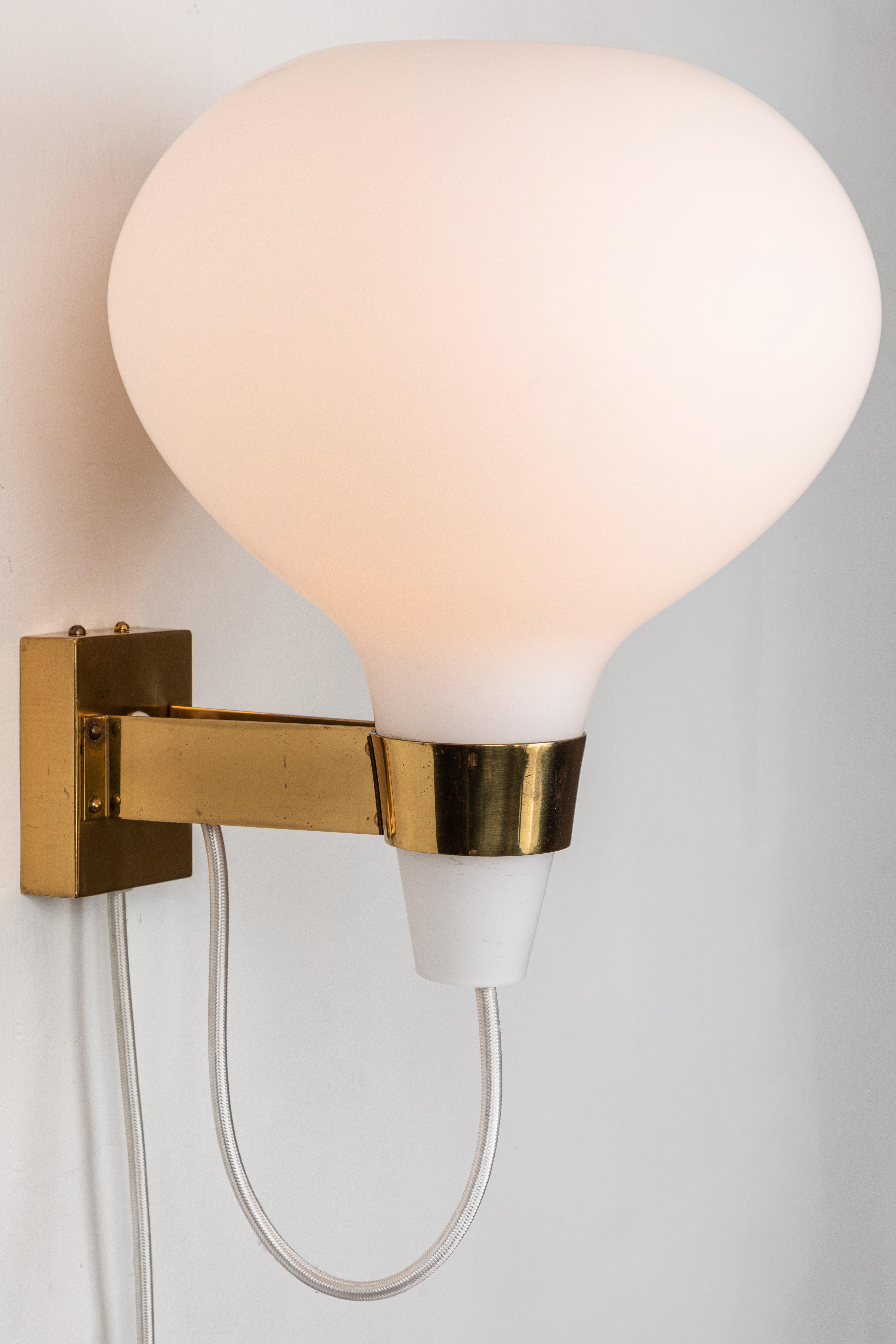 Large 1950s Lisa Johansson-Pape Bulbo glass and brass wall lamp for Orno. Executed in matte opaline white glass and patinated brass.

One lamp available. 

A contemporary of Paavo Tynell, the refined work of Lisa Johansson-Pape has made her an