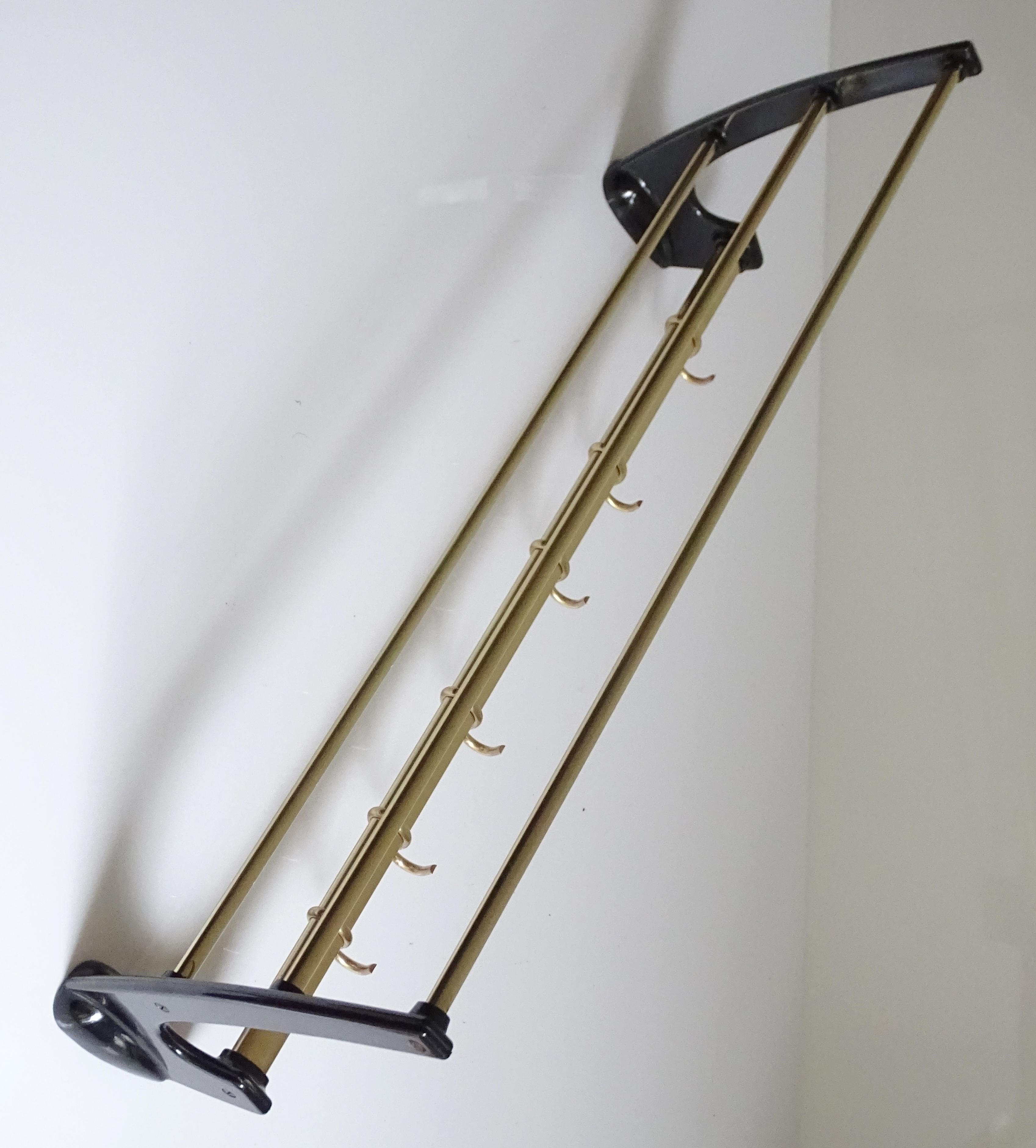 Original midcentury French wall-mount coat and hat rack, very elegant swooping design, made out of brass and black bakelite and six sliding hooks, 
restored and polished
Dimensions:
H 5.91 in. x W 24.81 in. x D 10.24 in.
H 15 cm x W 63 cm x D 26