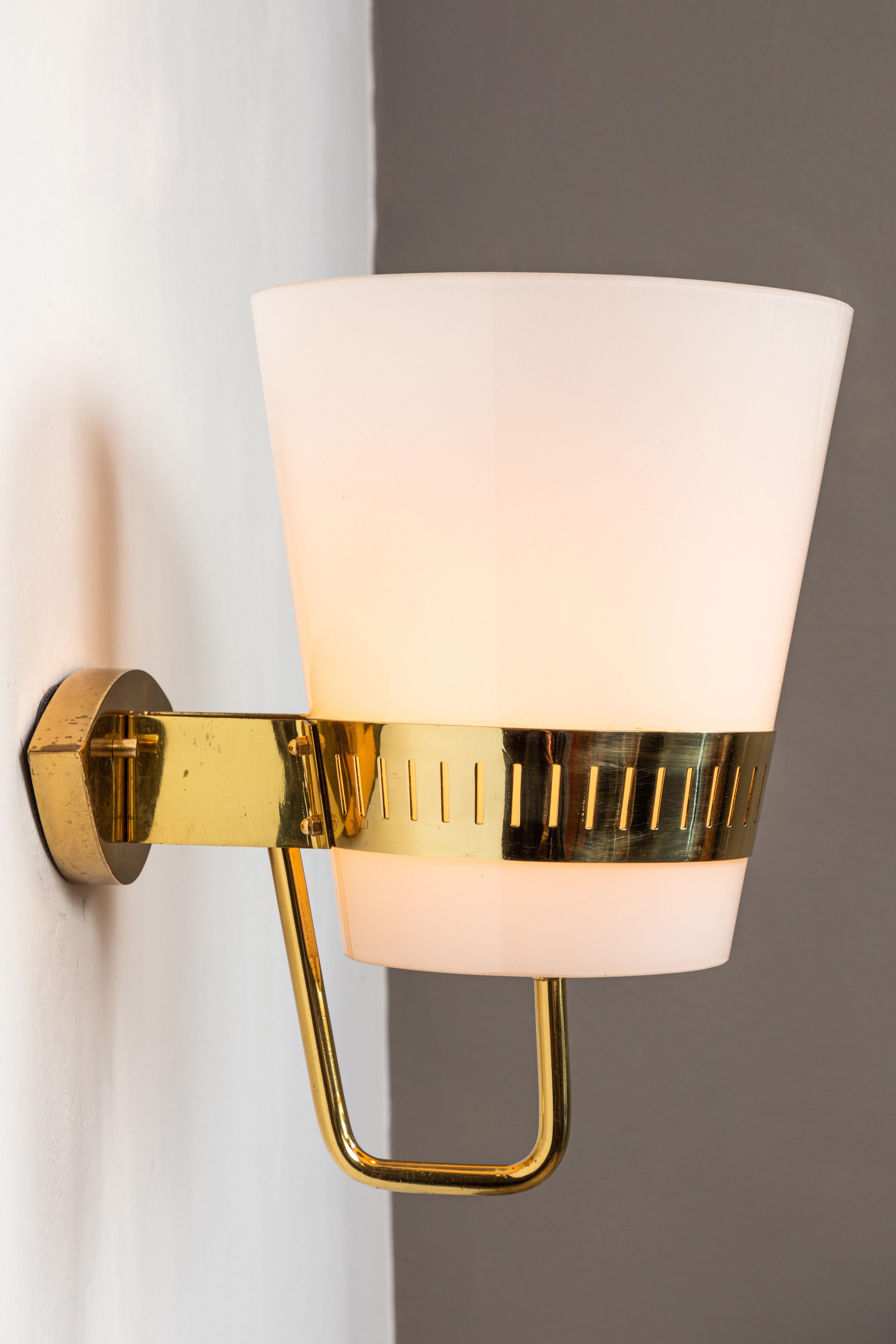 Large 1950s Stilnovo brass and glass sconce. Executed in brass and thick opaline glass, with original unmodified cat eye shaped sculptural Italian brass backplate. A sculptural and refined design of attractive scale that is in many ways