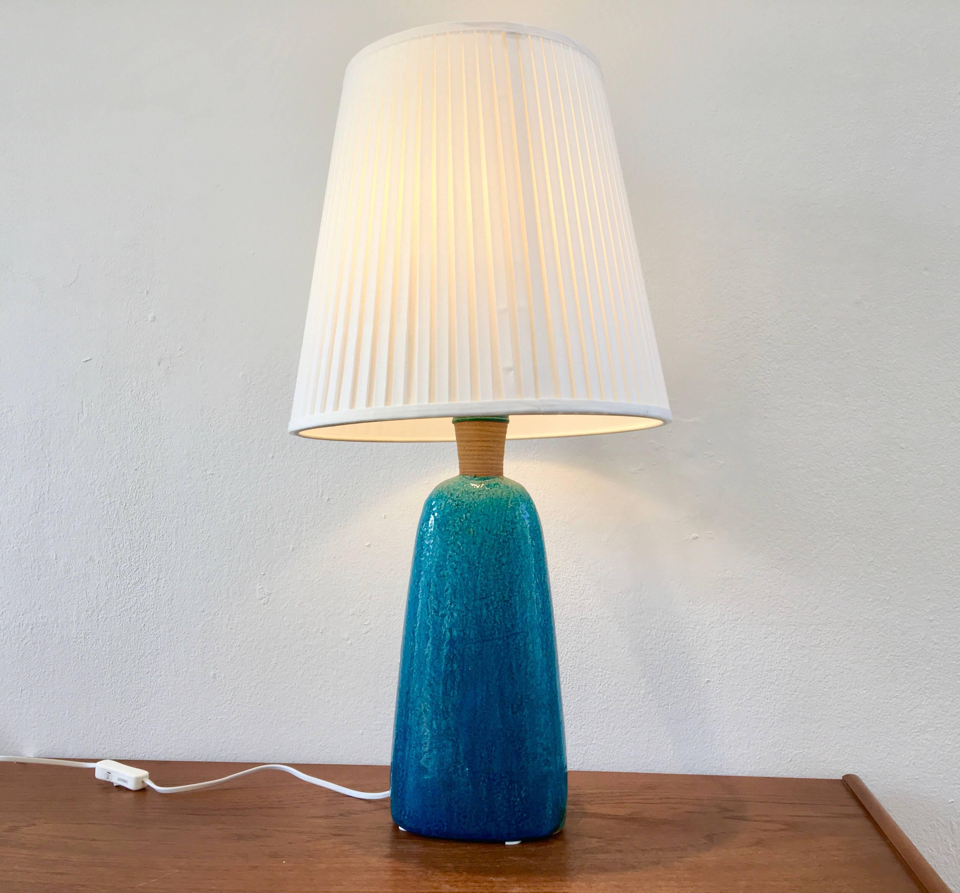 This large stoneware table lamp was designed by Nils Kähler and made in the 1950s by Herman A Kähler Ceramic (HAK) in Denmark. It has a turquoise colored glaze. The lamp has been rewired with a switch, new socket and a new shade. The lamp is signed