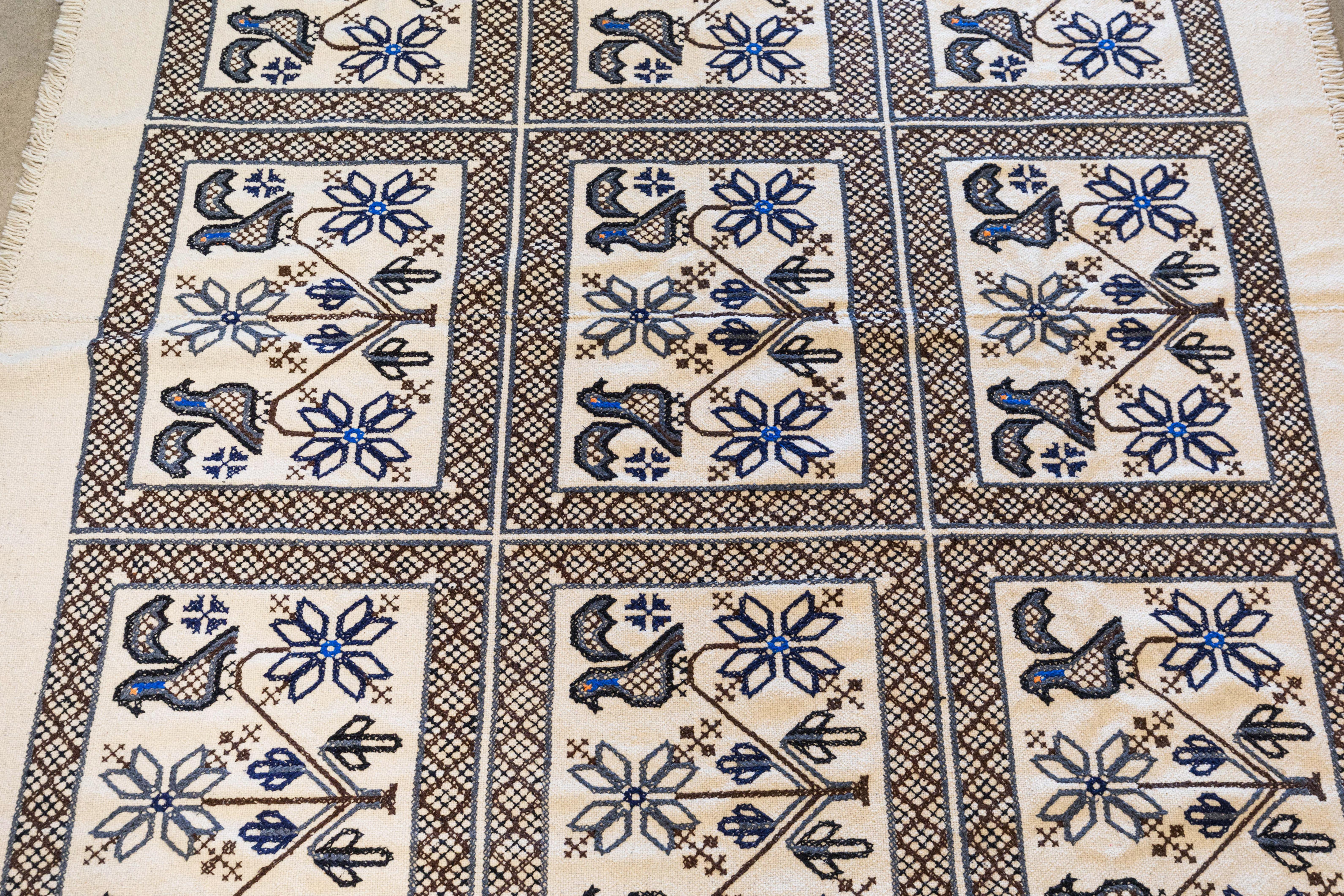 This large midcentury Mexican folk textile with handstitched embroidery would make a good floor covering, lightweight rug, bed cover, or wall hanging. Woven in cream wool, it features birds and a geometric design in black, blue, brown, and grey