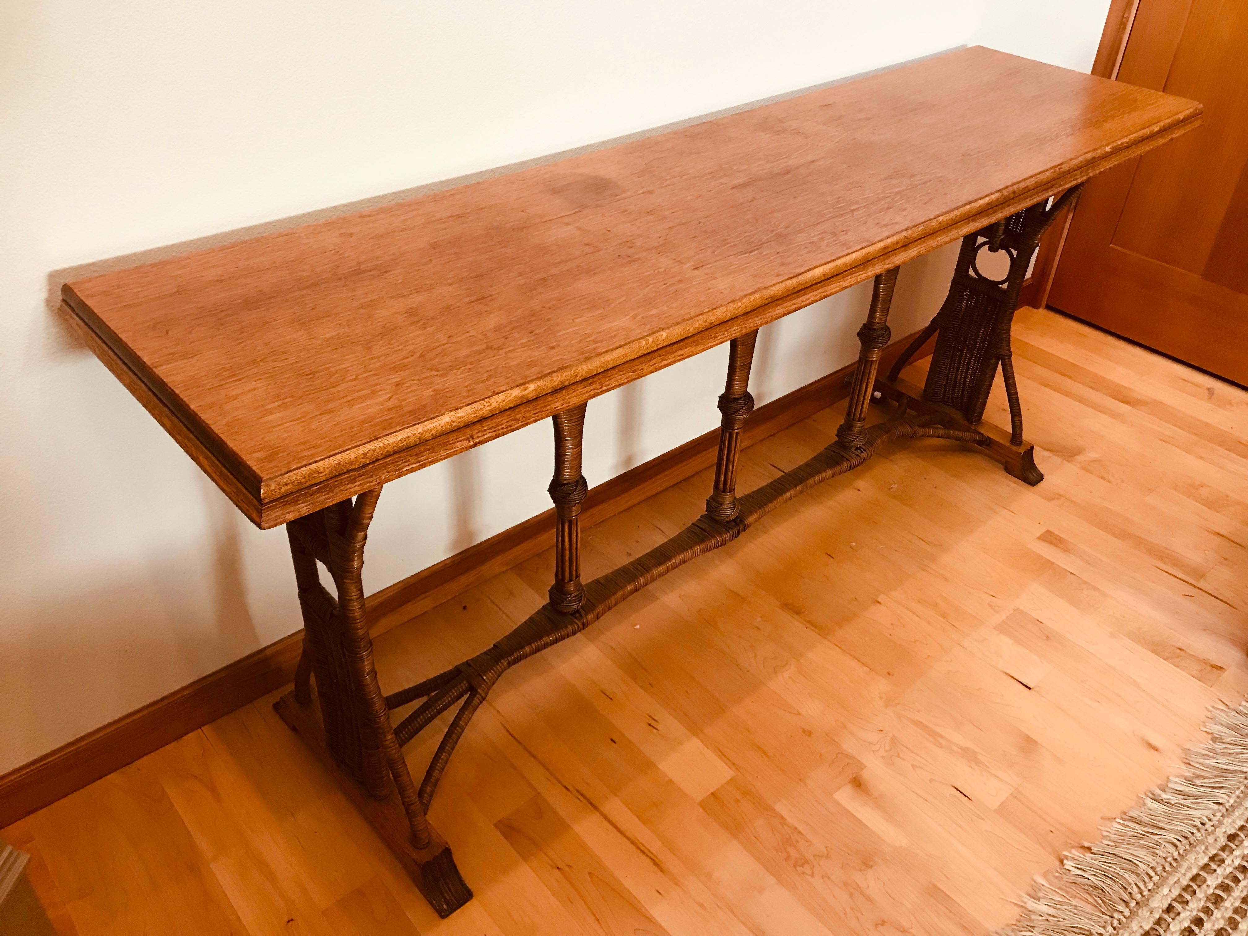 A custom 1960s oak top and rattan base large console table with oak claw carved feet. Made for an Astoria, Oregon Hotel. Great original patina.