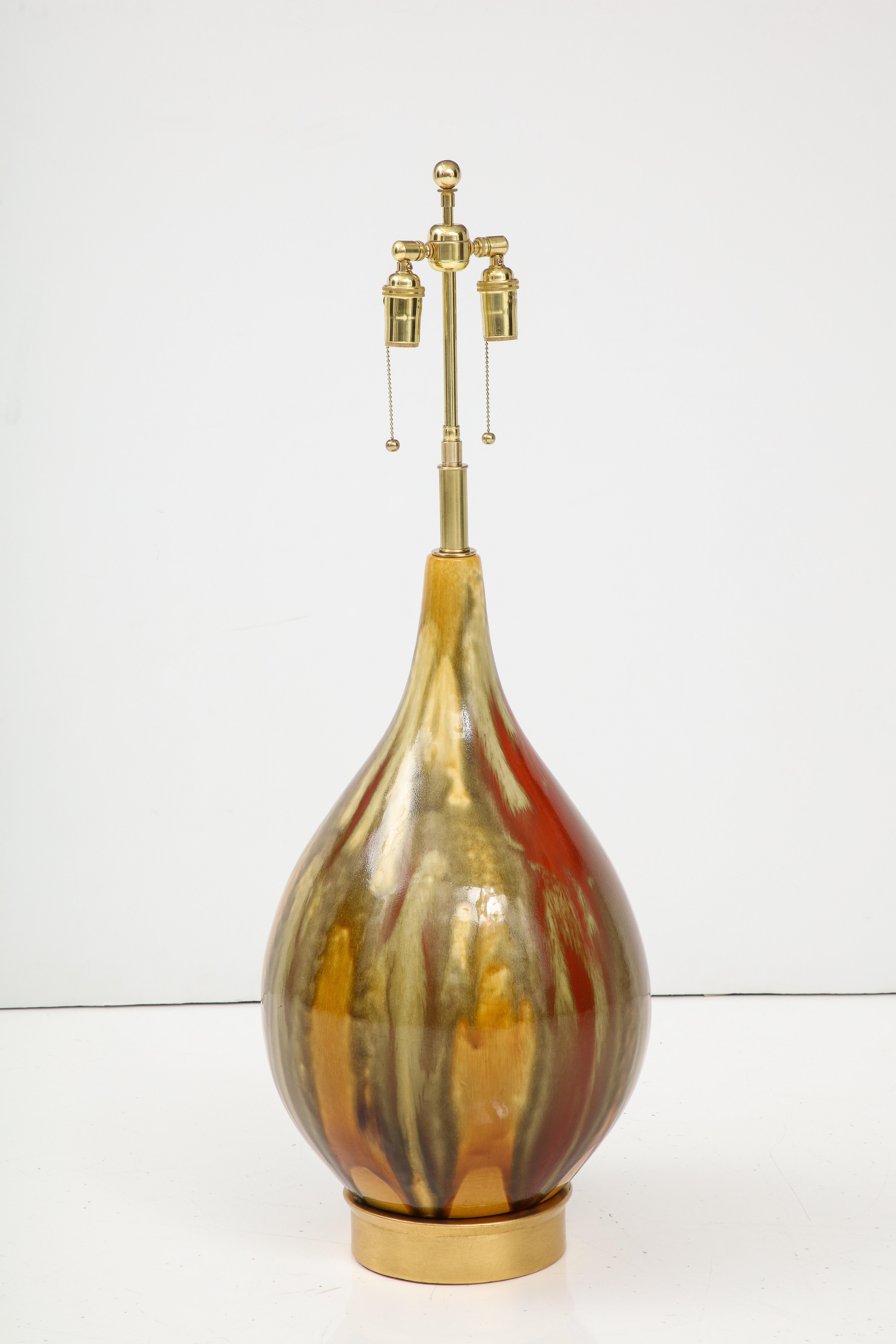 Grande lampada in ceramica italiana degli anni '60 con una bellissima finitura smaltata.
La lampada poggia su una base con foglie dorate e il gas è stato appena ricablato con un cavo regolabile. 
Corde doppie in ottone lucido che accolgono lampadine