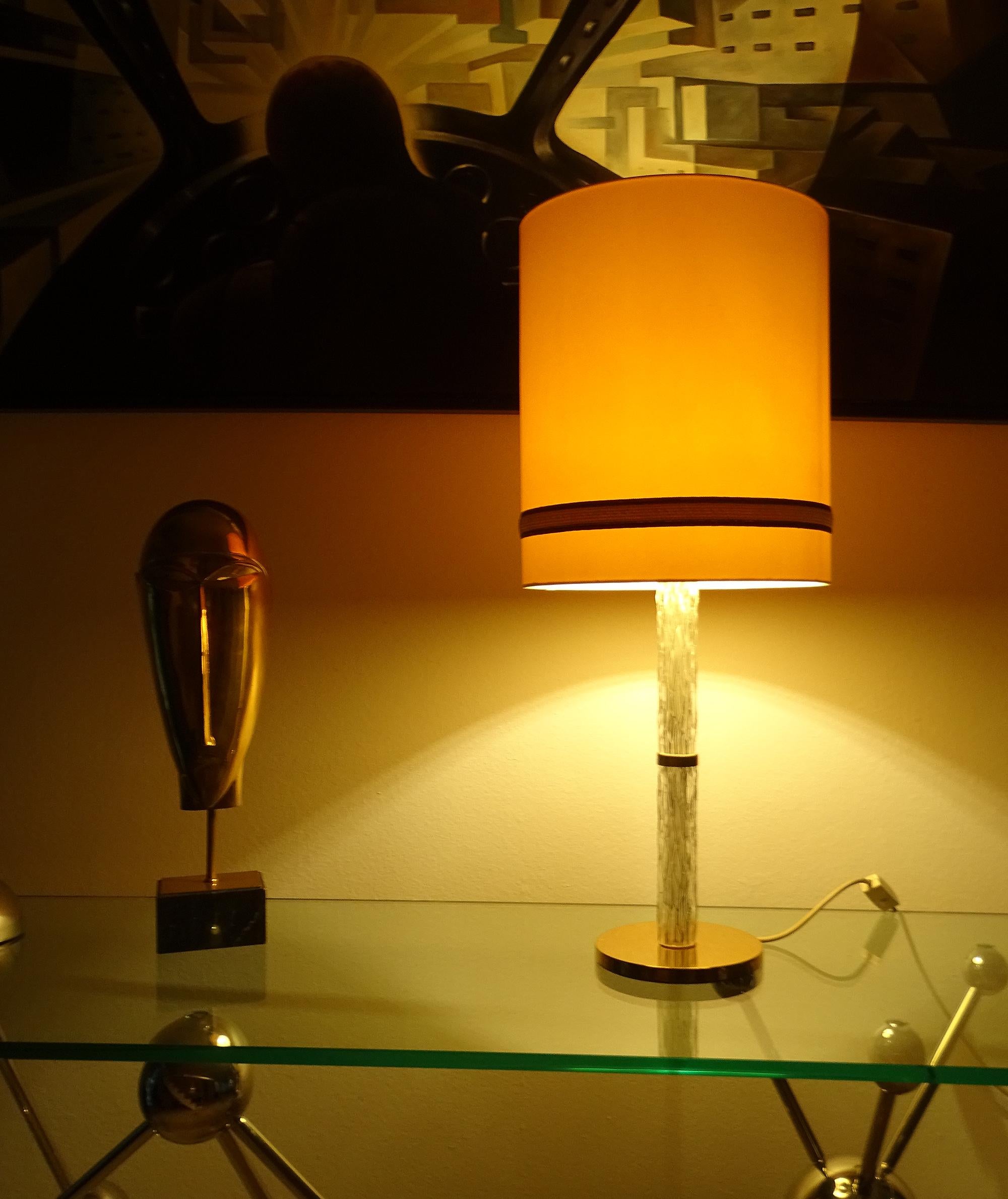 Large table lamp by Kaiser, circa 1965-1970, featuring a structured glass column with polished brass accents, large satinated cream and gold accents shade. The lamps have been tested with US American light bulbs under 120v and they work flawlessly. 