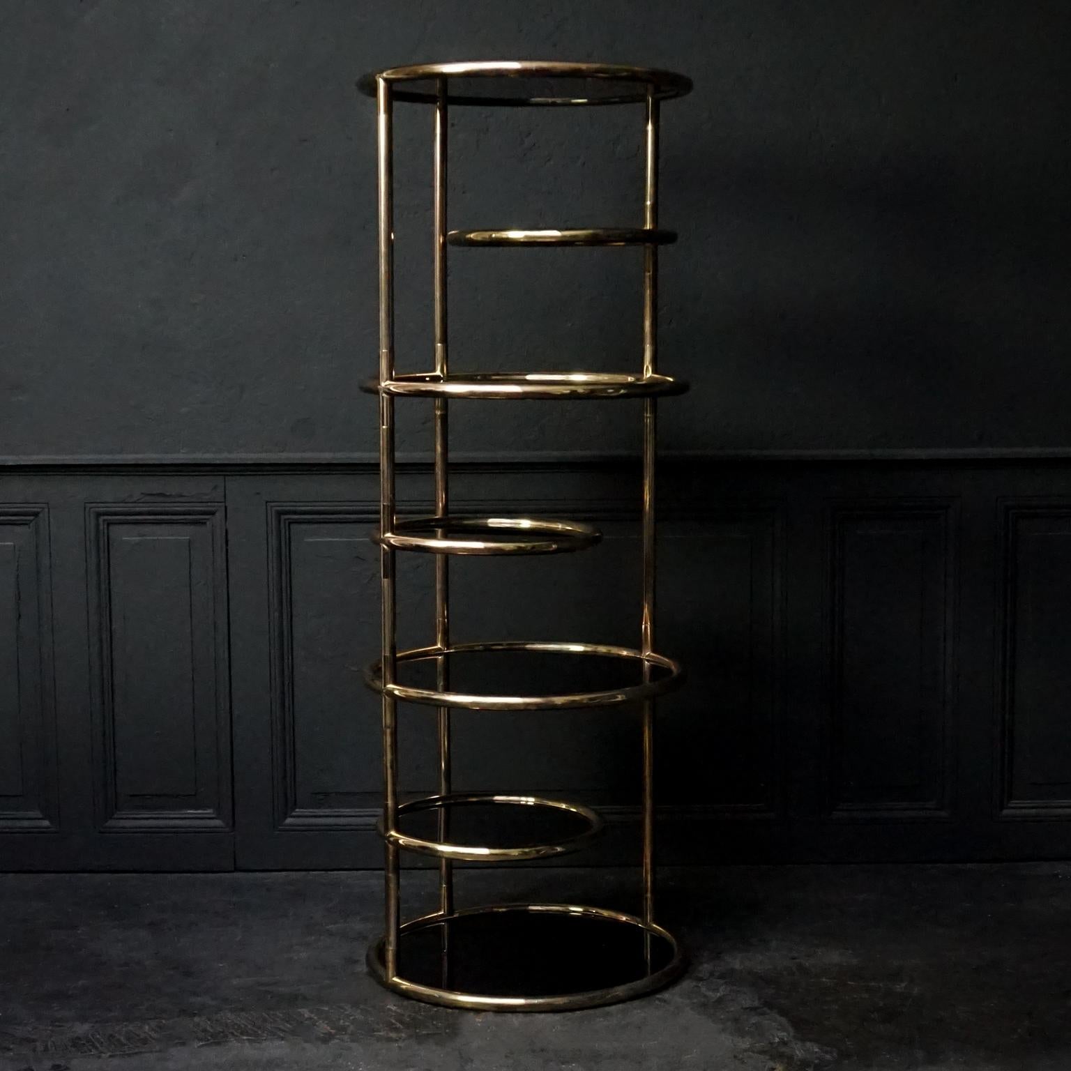Beautiful vintage midcentury Hollywood Regency round brass and smoked glass seven tiered swivel étagère by or in the style of Milo Baughman.
Features seven circular 'shelf' surfaces. The three smaller ones swivel out independently to your desire and