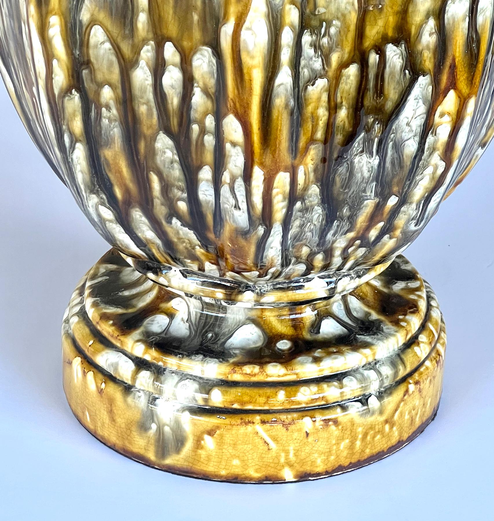 of large scale, the robust lamp of octagonal baluster form with everted lip above an ovoid body all resting on a splayed foot and circular base; decorated overall in a rich drip glaze in colors of ochre, green, brown and ivory; 18.5