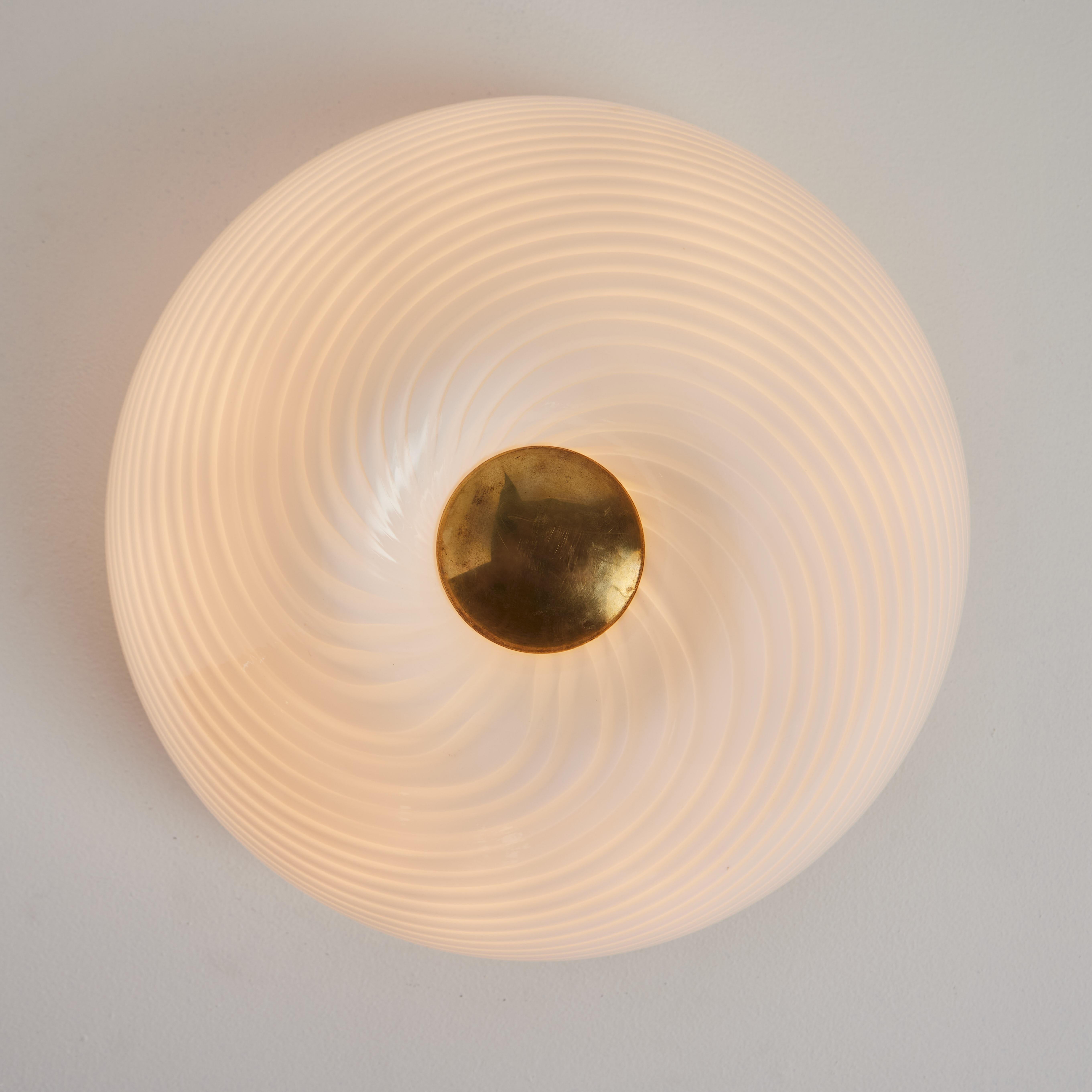 Large 1960s Vistosi Blown Murano Brass and Glass Wall or Ceiling Light.

Executed in blown Murano glass with a brass centerpiece, this rare flush mount features a distinctive spiral pattern and can be installed on either the wall or the ceiling. Its