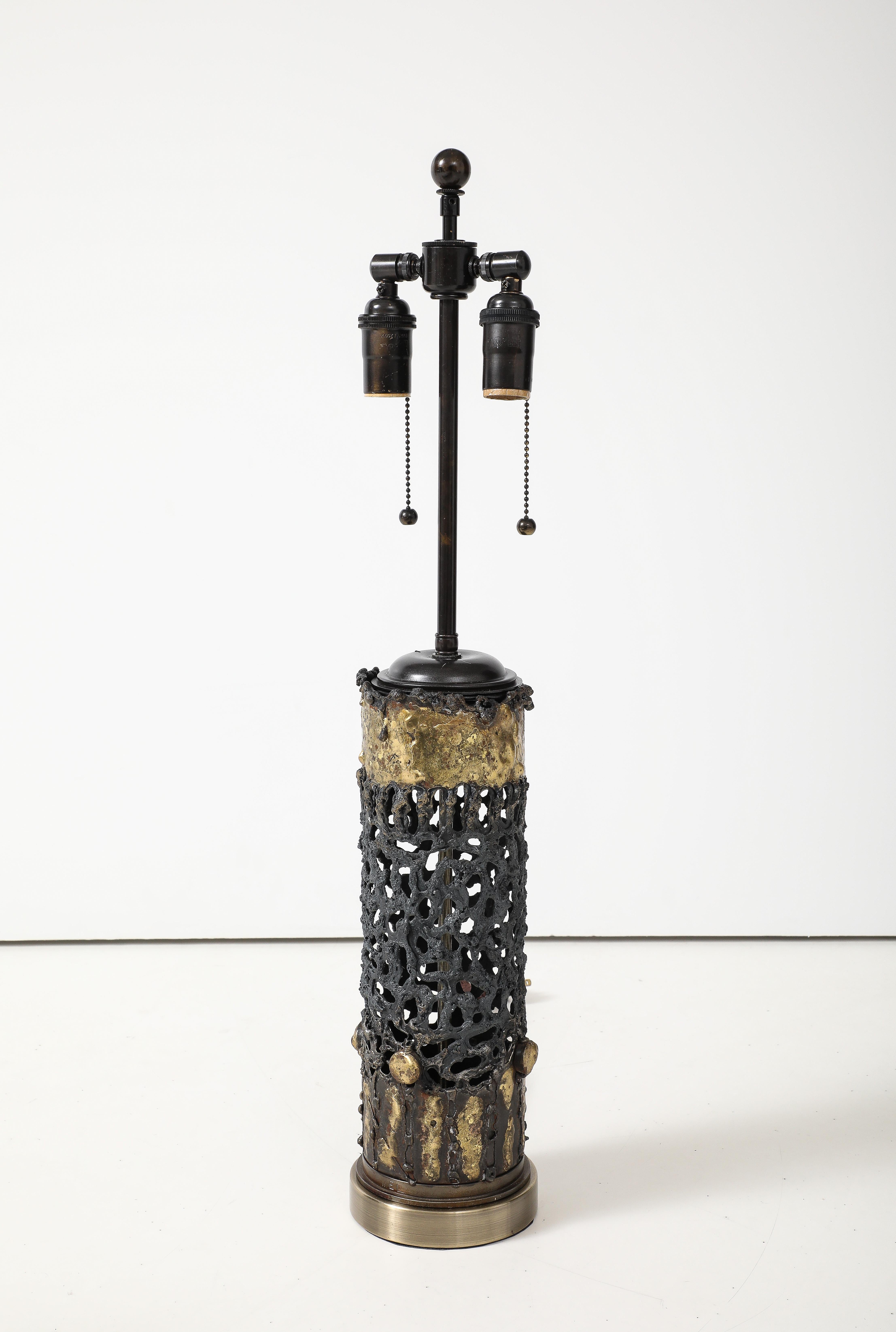  Große brutalistische Lampe aus Metall aus den 1970er Jahren mit einem gebrannten und durchbrochenen Design.
Die säulenförmige Leuchte hat ein wunderschönes unregelmäßiges brutalistisches Design in Gold- und Bronzetönen.
Die Lampe wurde neu
