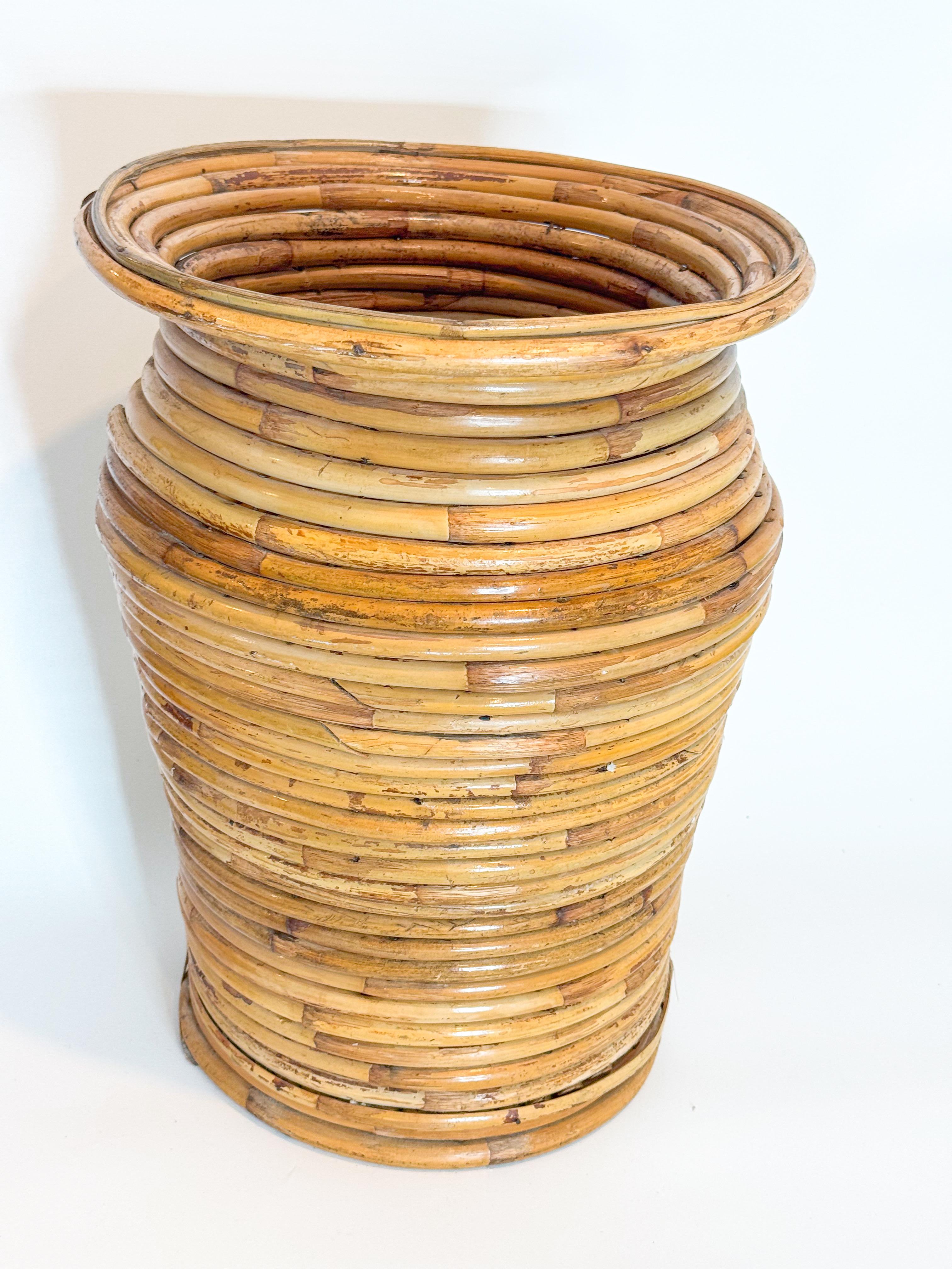 This large 1970s floor planter or vase is handcrafted from coiled pencil reed with a sculptural, tapered silhouette and warm honey finish. The piece showcases the signature organic elegance of mid-century Italian design, reminiscent of the work of