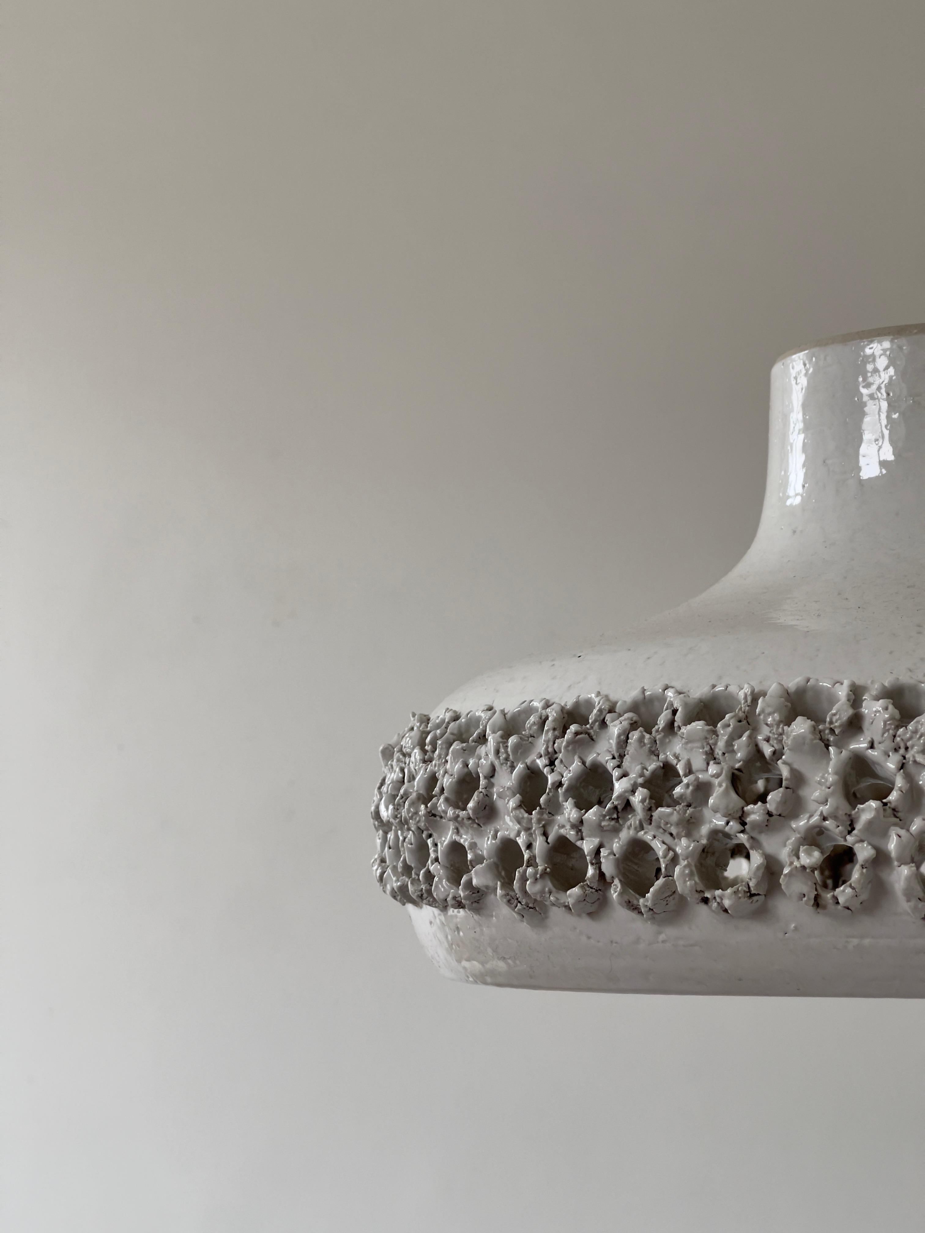 Rare and large perforated stoneware pendant in white glaze by ceramist Aksel Larsen for Axella in the 1970s. Hanging in a patinated metal chain and have a stoneware ceiling cup. The lamp is in a very good condition. No chips or scratches just a