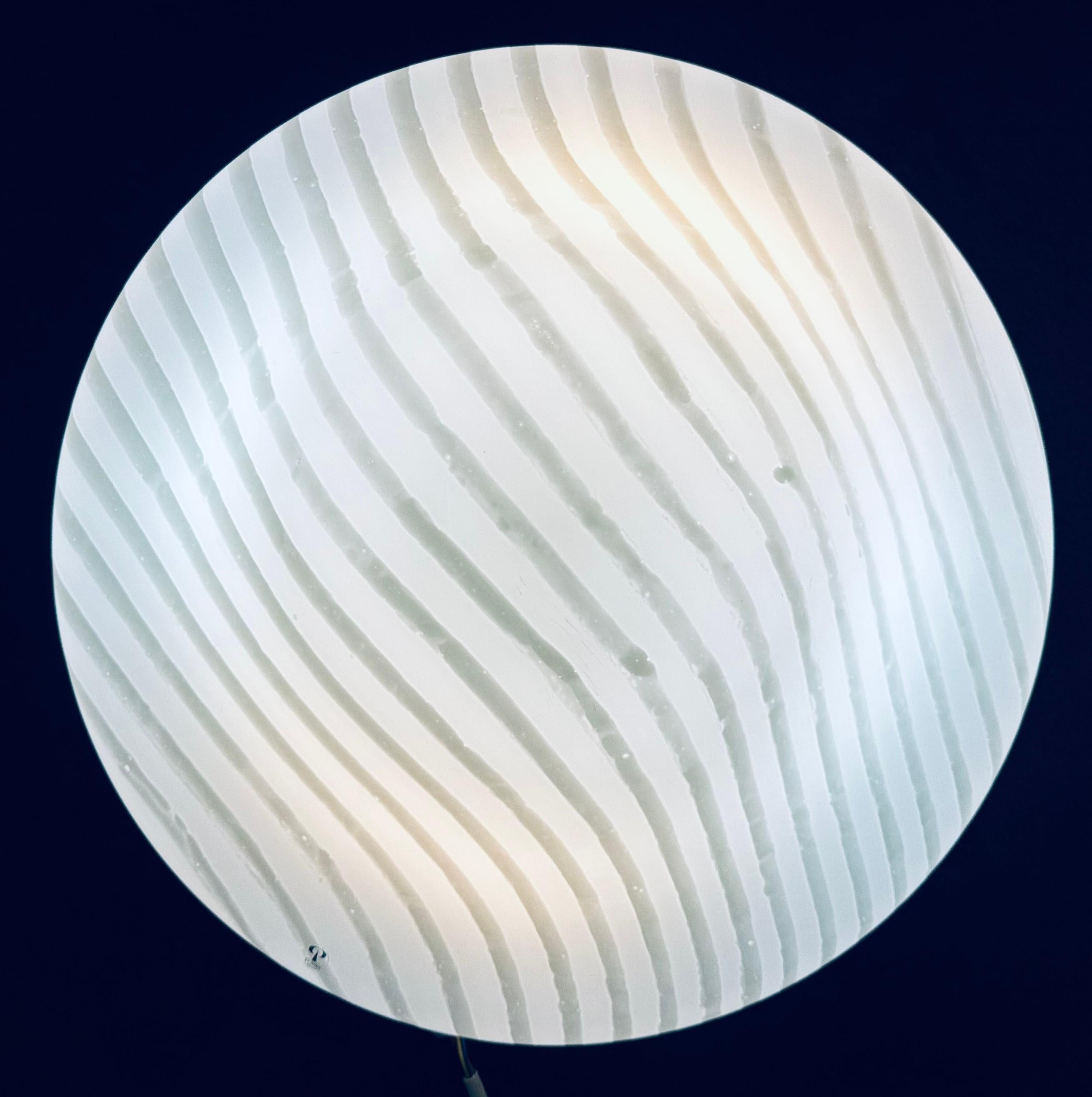 A usually large 1970s German Peill & Putzler plafoniere, space-age, opal glass with a lighter striped pattern flush mount ceiling light.  The opal striped-glass circular shade is fixed onto the white lacquered metal frame/bulb holder with three