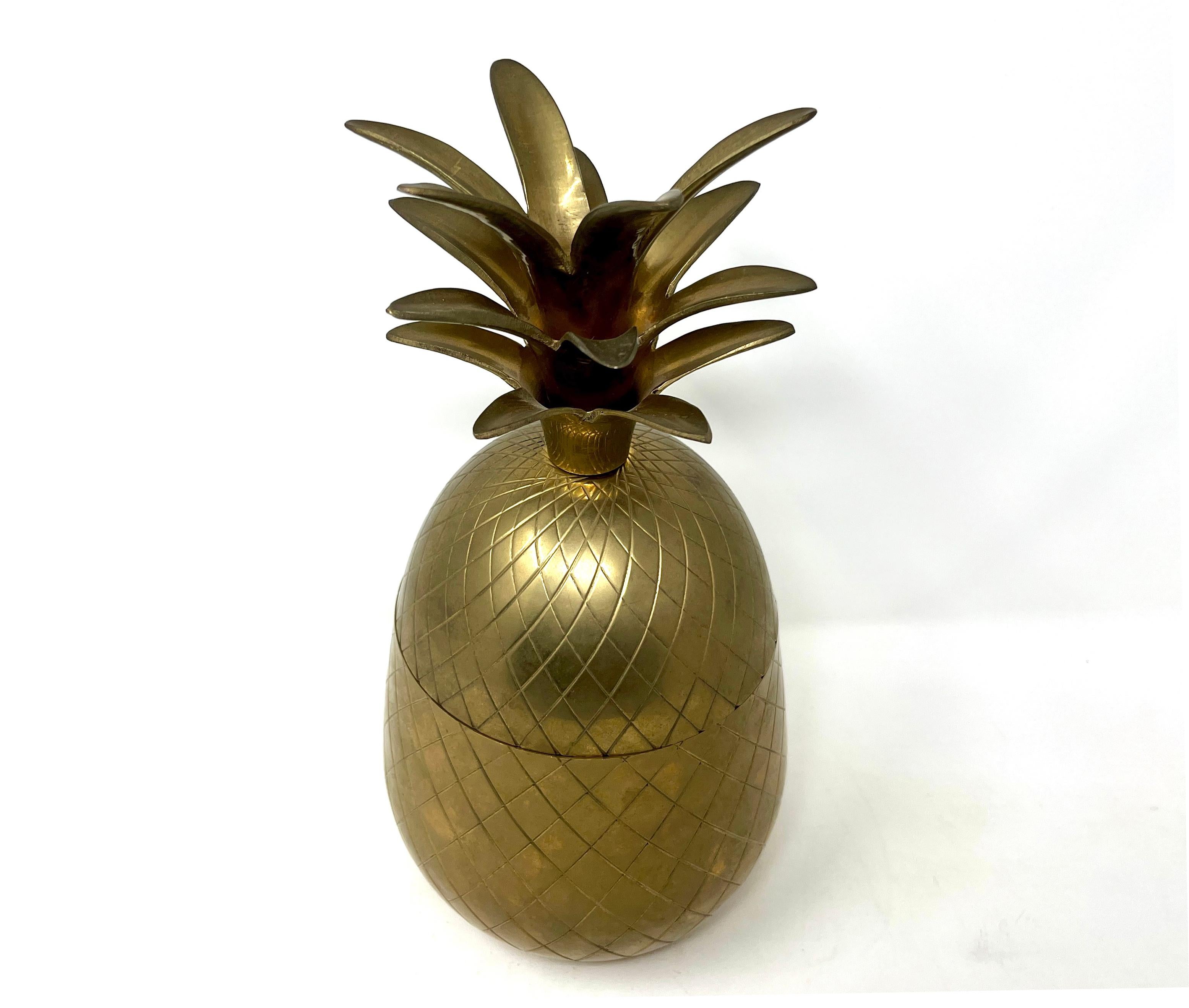 Circa 1970s vintage Hollywood Regency polished brass pineapple ice bucket. The surface of the outside is decorated with an incised diamond pattern. The ice bucket separates in two allowing access to whatever you decide to keep inside. Lovely