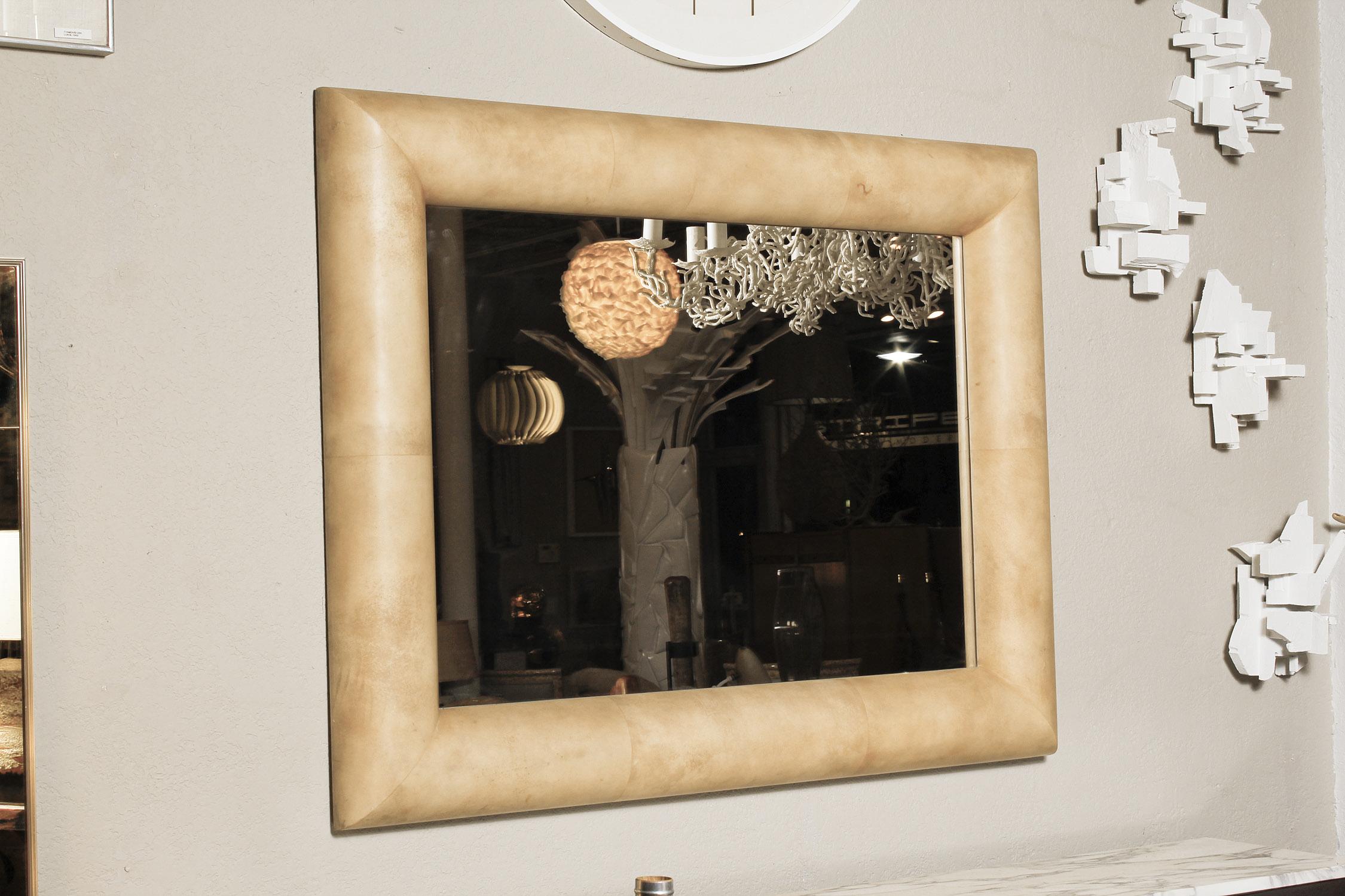 Ein Spiegel mit Stiernase aus den 70er Jahren in der Art von Karl Springer hat ein sattes, satiniertes Ziegenleder in warmen Gold- und Karamelltönen. Kann senkrecht oder waagerecht aufgehängt werden.