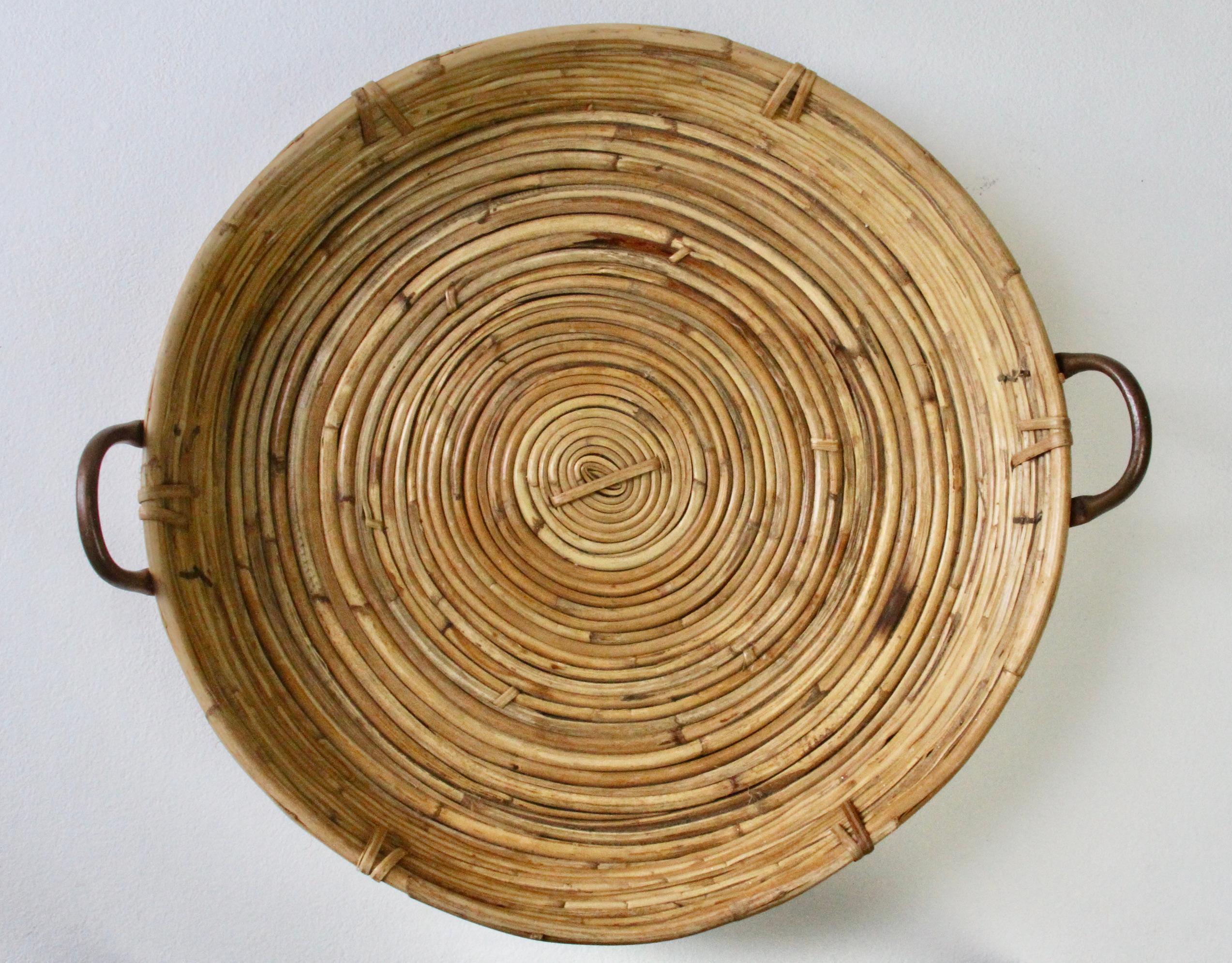 Grande vassoio, supporto, supporto o piatto da portata rotondo e circolare vintage Mid-Century modern Hollywood Regency realizzato in Italia, circa anni '70. Realizzato in bambù e rattan intrecciato con maniglie in ottone per il trasporto, che