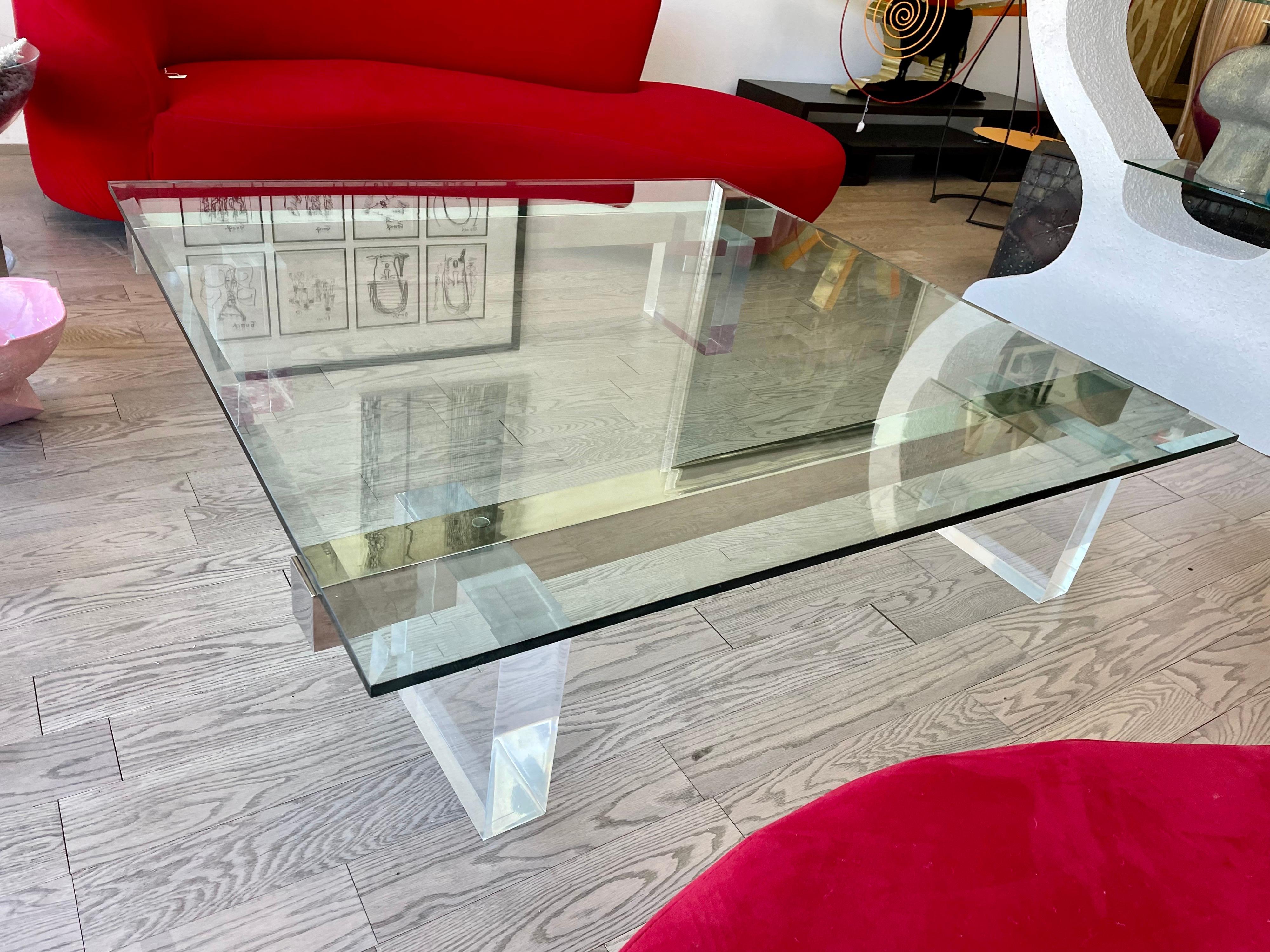 Very stylish large 1980s lucite coffee table in very good condition.
The base of this coffee table is composed by four thick lucite pedestals and two stainless steel bars resting on top.
The glass top is 3/4 of an inch thick with few hairlines