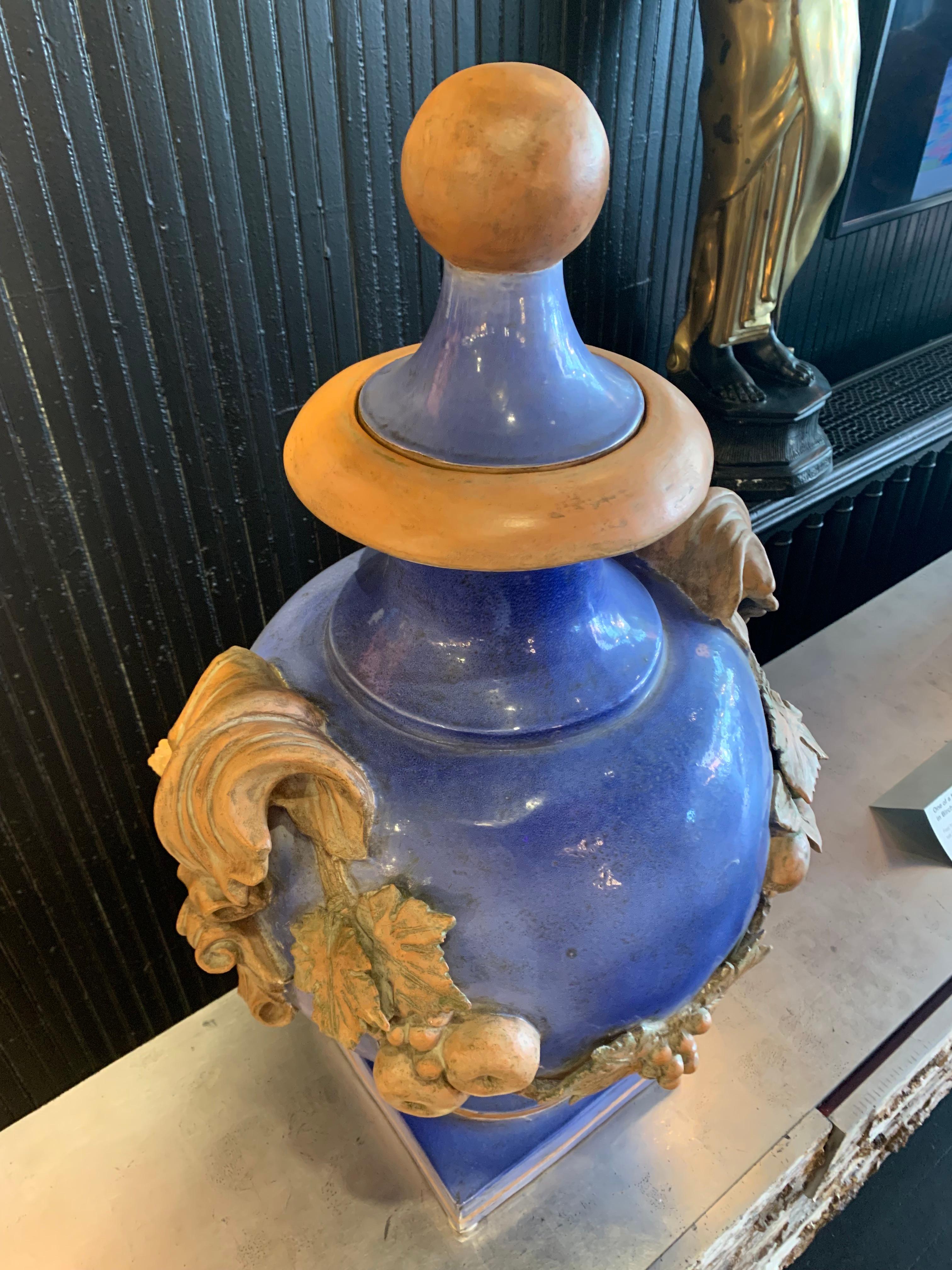 Ceccarelli Ceramics (Italian), contemporary. Pair of heavy blue glazed ceramic lidded urns with terracotta colored handle, fruit, and leaf accents. Signed at base. These lidded urns are classic and timeless in appearance. Each decoration of the vase