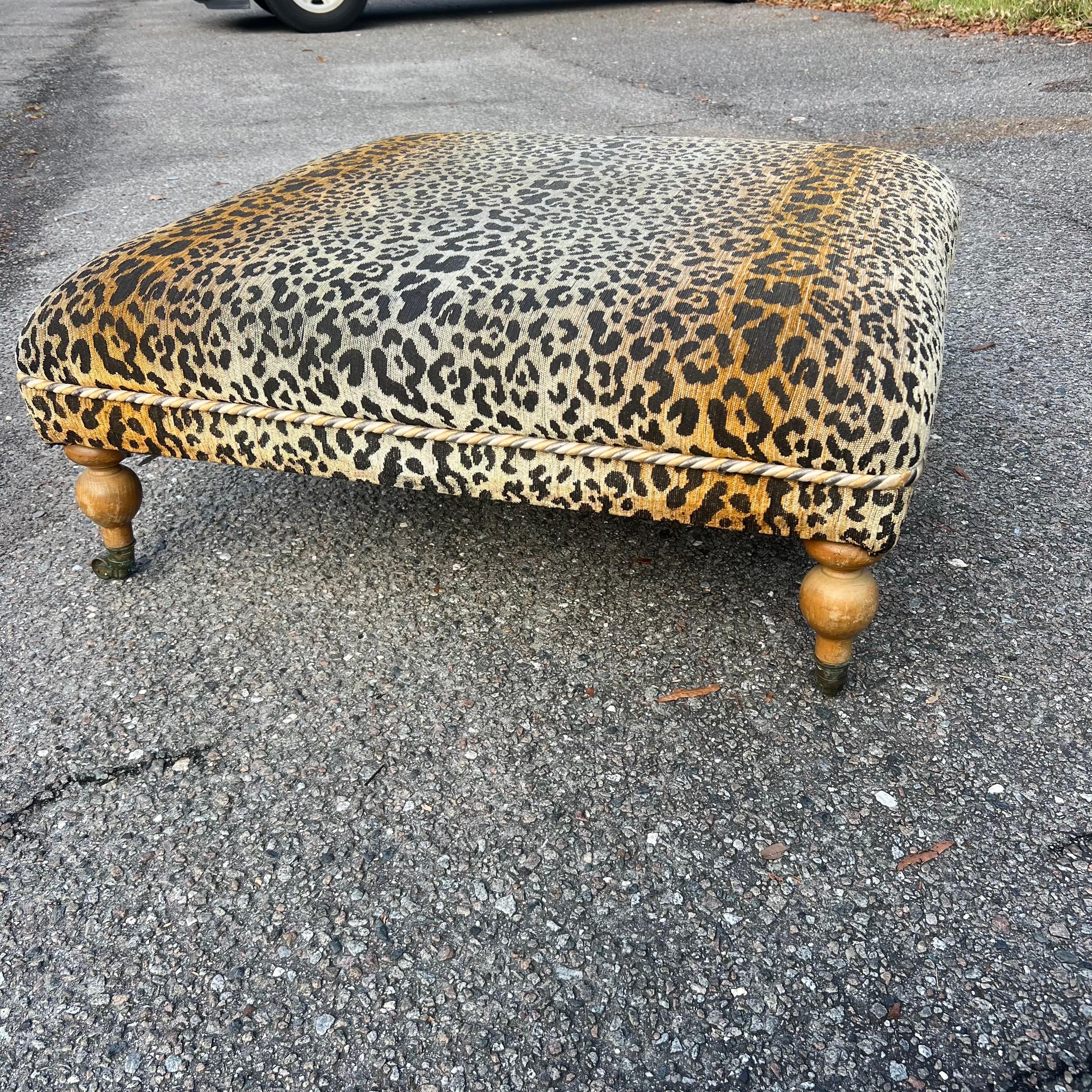 Large custom made coffee table sized ottoman with turned wooden legs on metal castors.  Previously upholstered in a leopard print fabric.  Very well made and upholstery is in very good condition. Circa late 20th century