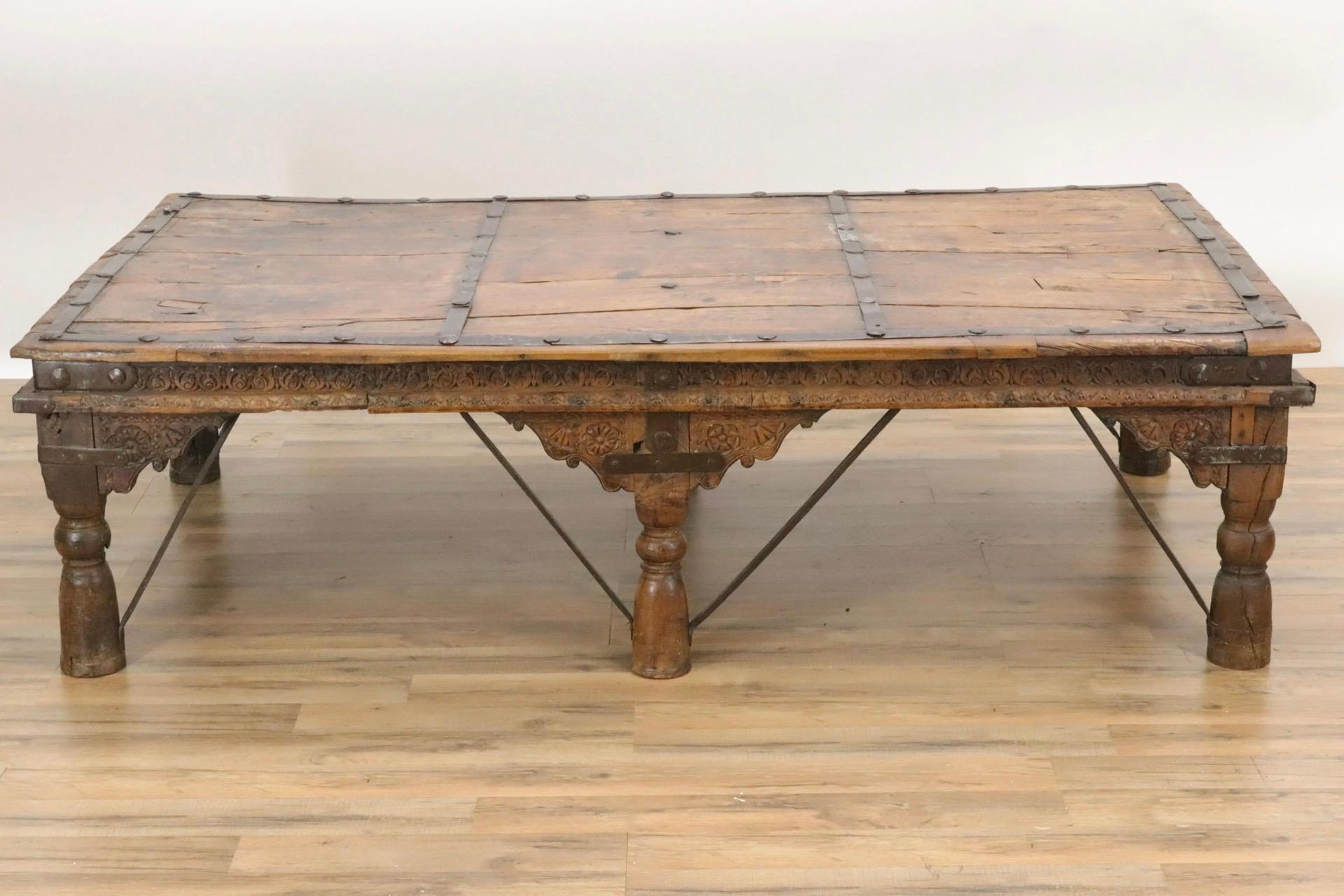 Large and impressive, this plank table top is made with unusual curved wood pieces. Table is supported by six turned legs and iron braces with intricate carved decoration on the apron. Metal strapping and iron bracing serve both as decoration and