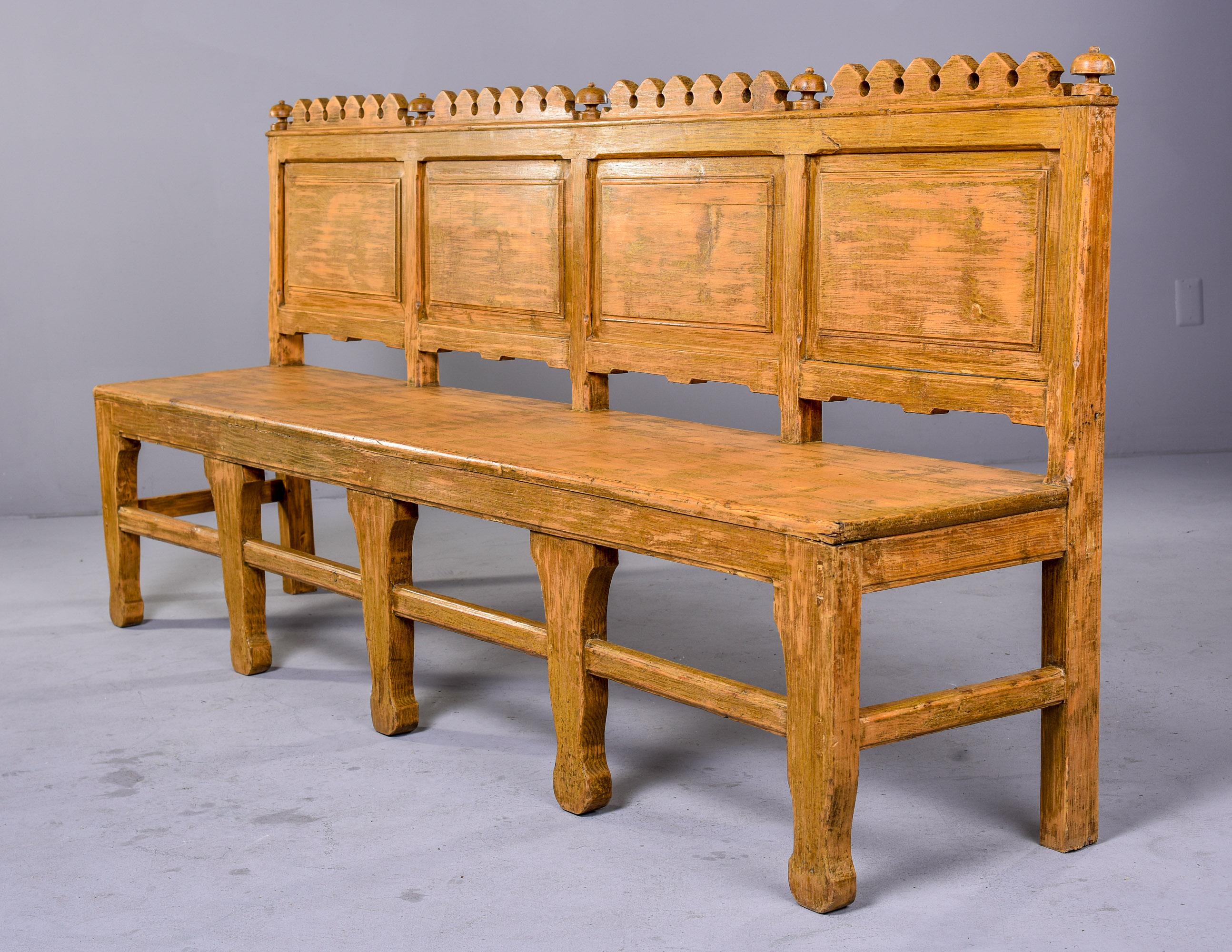 Found in England, this circa 1880s bench has seven legs, a front stretcher and four back rest panels with carved details at the top. May originally have been a church pew but we can’t be sure. Pale muted pumpkin color paint does not appear to be
