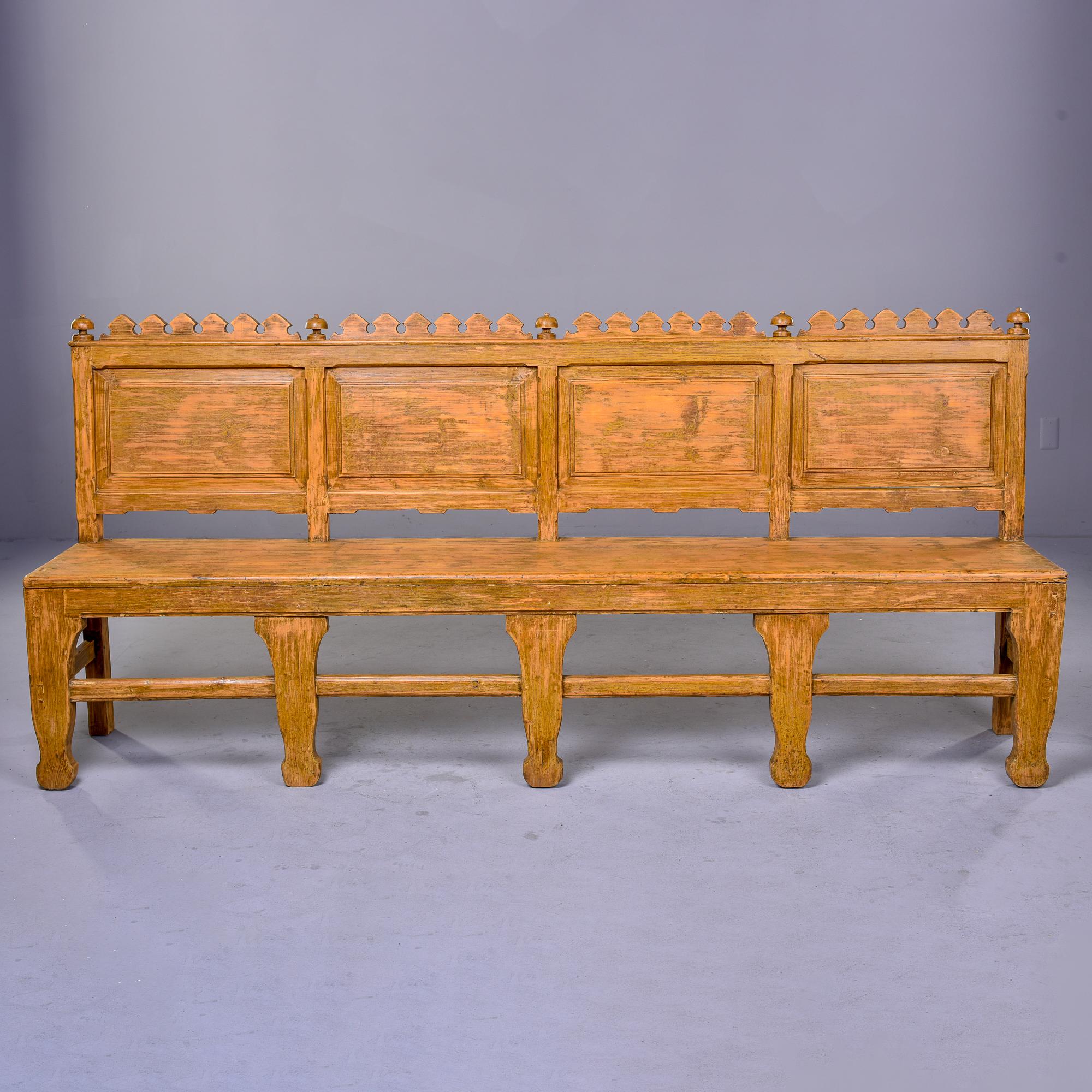 Found in England, this circa 1880s bench has seven legs, a front stretcher and four back rest panels with carved details at the top. May originally have been a church pew but we can’t be sure. Pale muted pumpkin color paint does not appear to be
