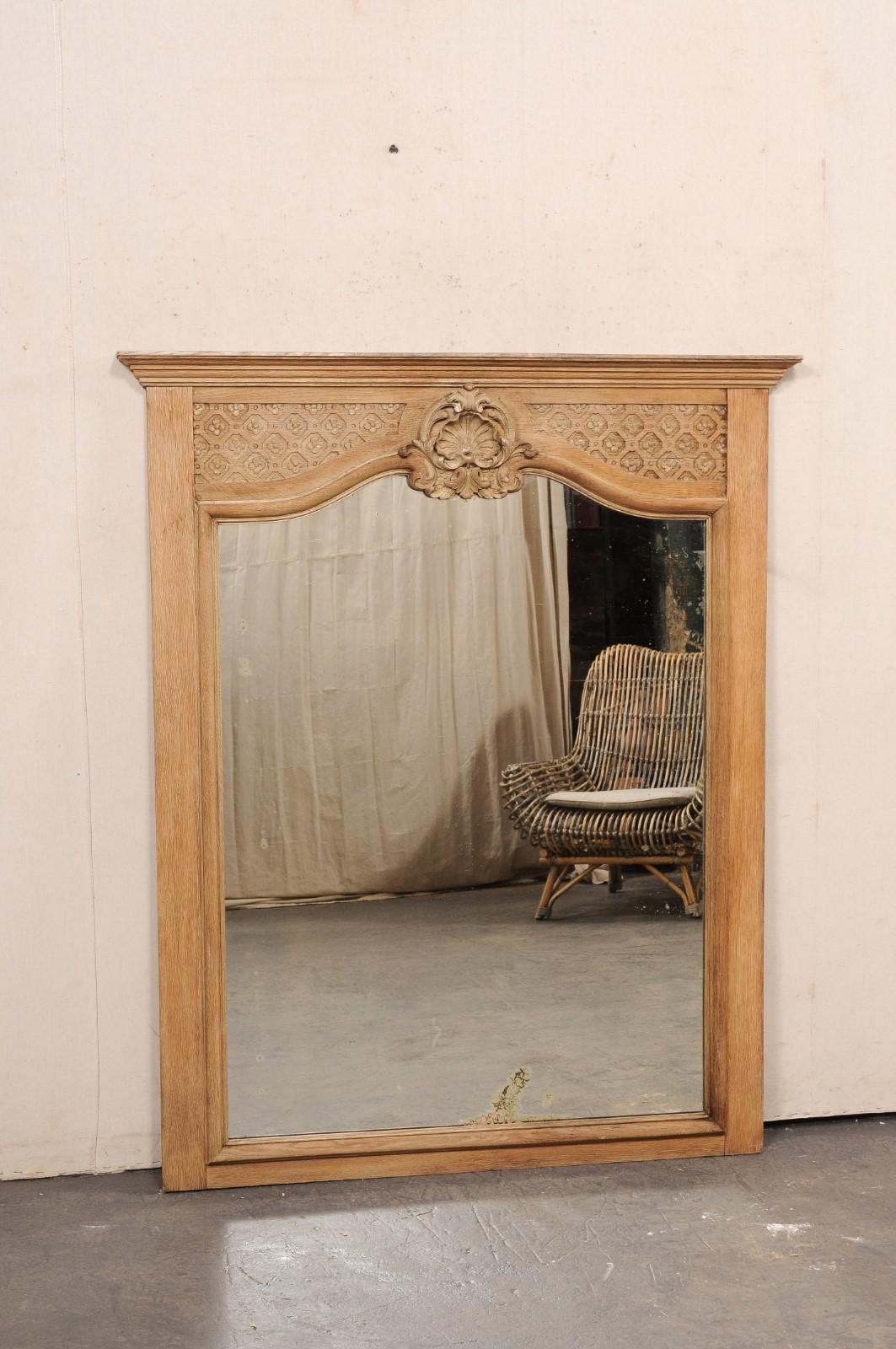 Miroir français de grande taille en bois sculpté, avec sa vitre d'origine, du 19e siècle. Ce miroir ancien de France est placé dans un cadre de forme rectangulaire, avec une garniture moulée sur la traverse supérieure et un motif floral répétitif