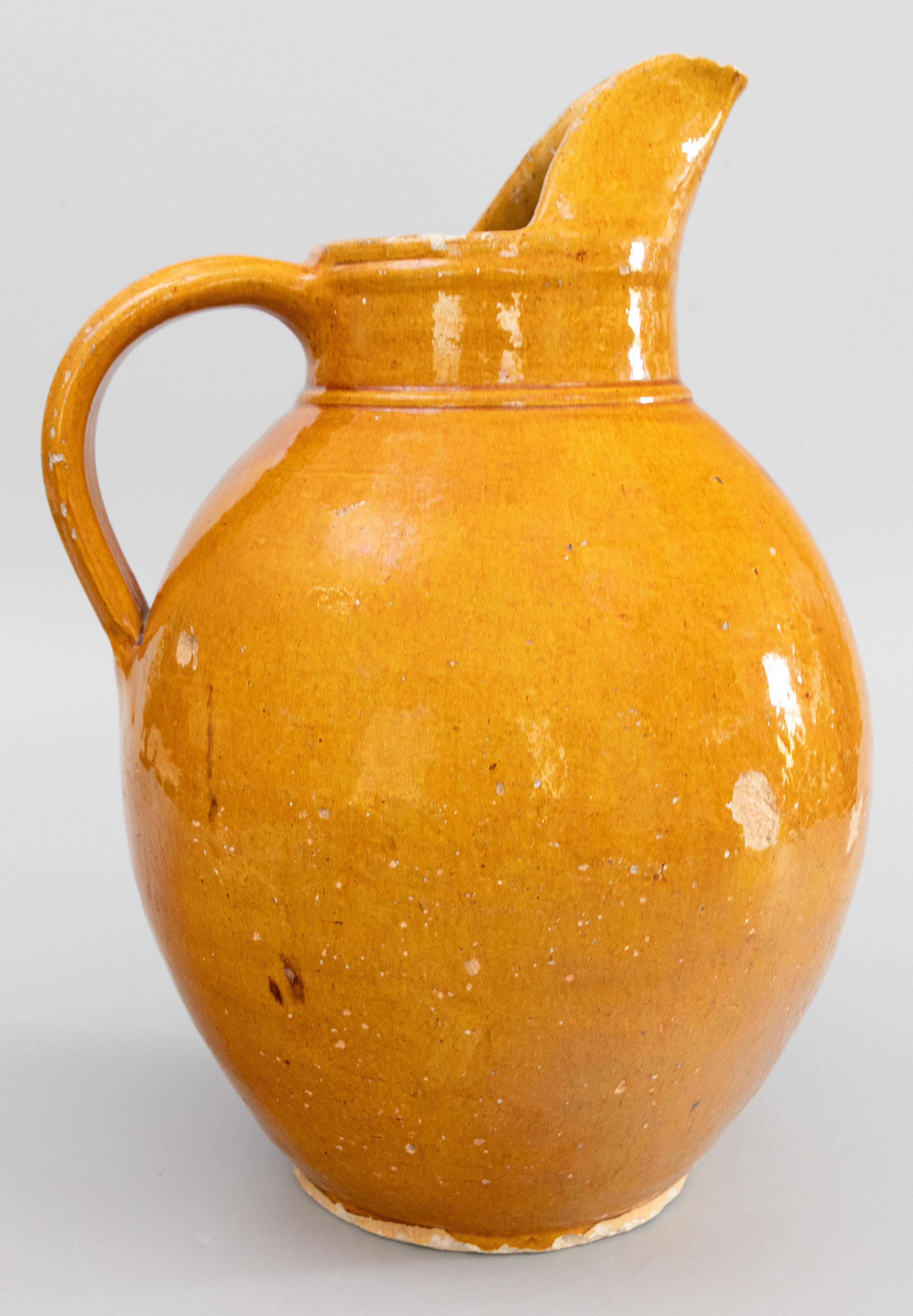 A lovely antique 19th-Century Country French ocher yellow glazed terracotta pottery Provençal pitcher/ jug / wine ewer from Provence in southeastern France. This charming piece is a nice large size with a shaped spout and bulbous design in a lovely