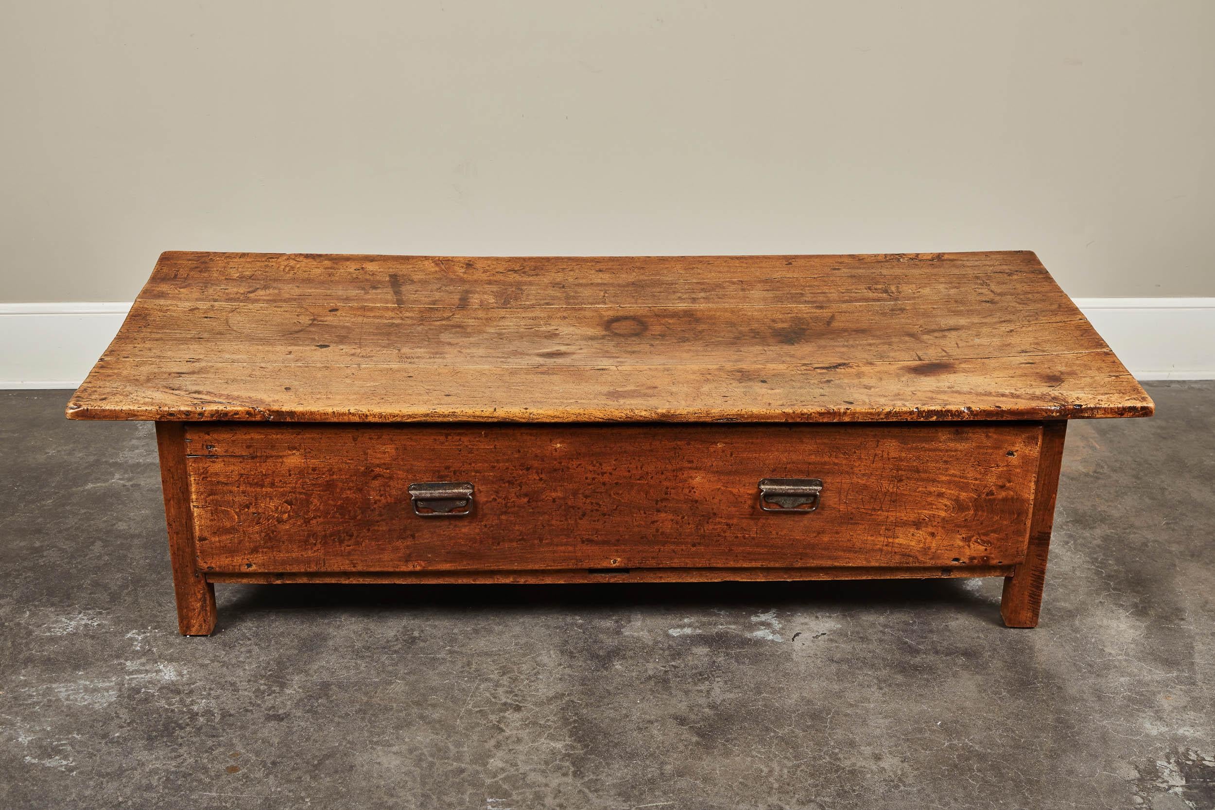 A large 19th century French farmhouse table. Was previously cut down to coffee table height, from an old work table. The drawer has angled sides, likely noting flour storage or dry goods storage. Gorgeous patina throughout.