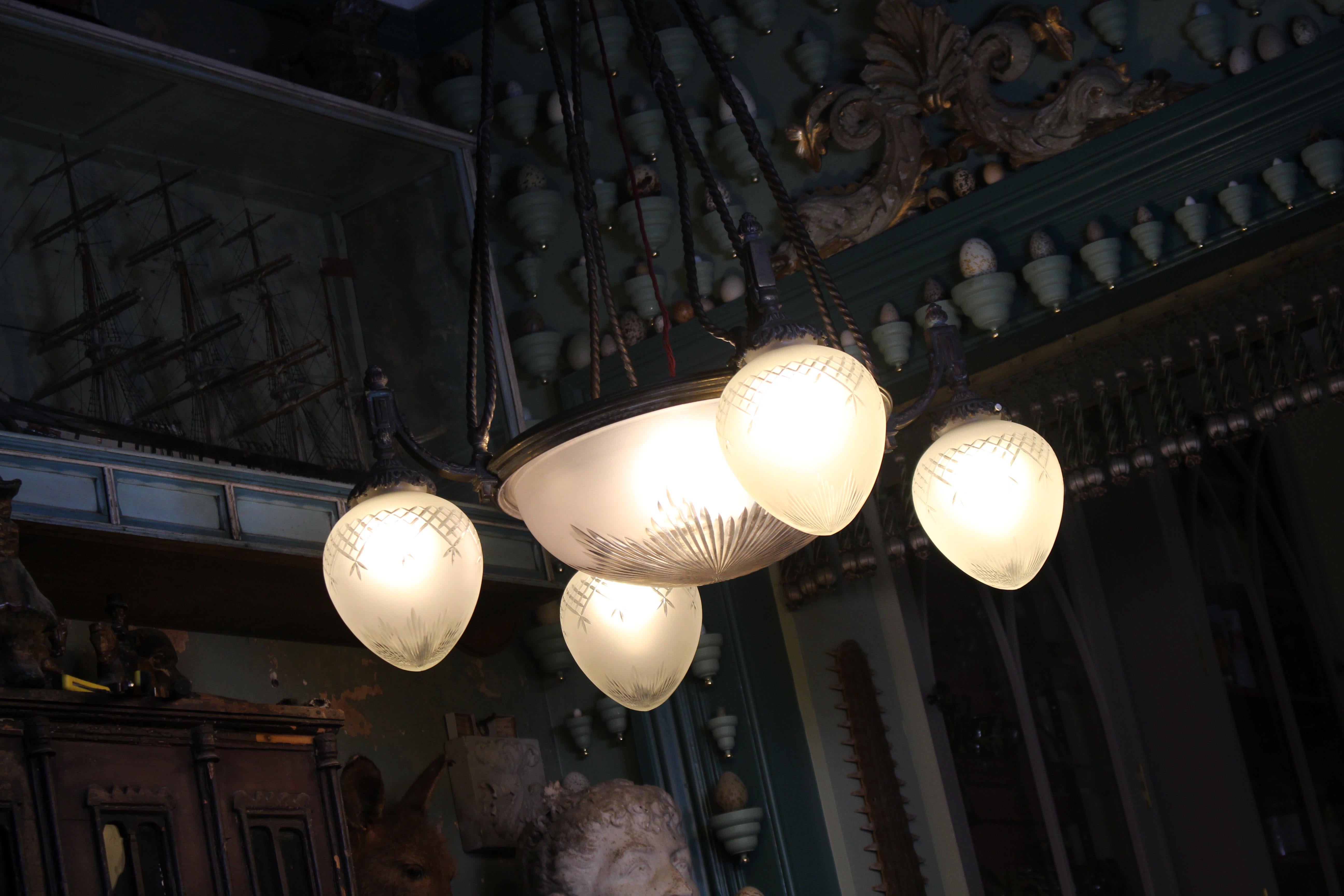Un grande lampadario regency revival in bronzo e vetro di qualità eccezionale. Bronzo fuso di grosso calibro, con dettagli decorativi a chiave greca, fogliame e steli di corda finta. 

L'ossidazione del metallo è dovuta all'età, mentre i vetri sono