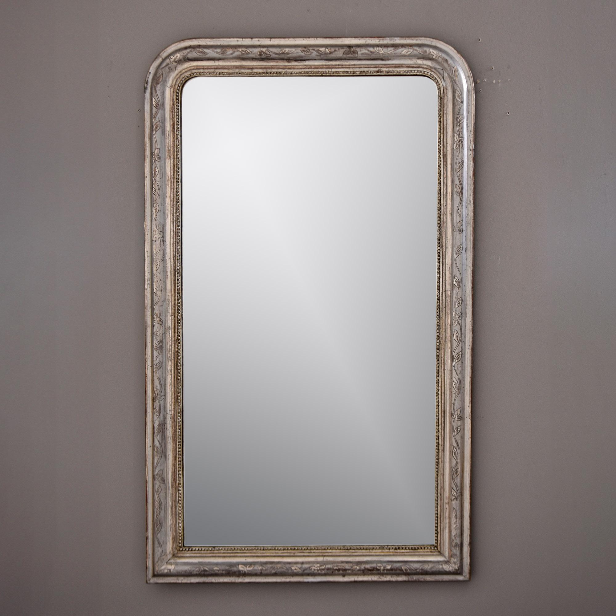 Trouvé en France, ce miroir encadré de feuilles d'argent date des années 1870. Le cadre classique de style Louis Philippe présente une subtile bordure gravée de vigne feuillue sur la surface supérieure, avec un bord intérieur perlé. Le miroir