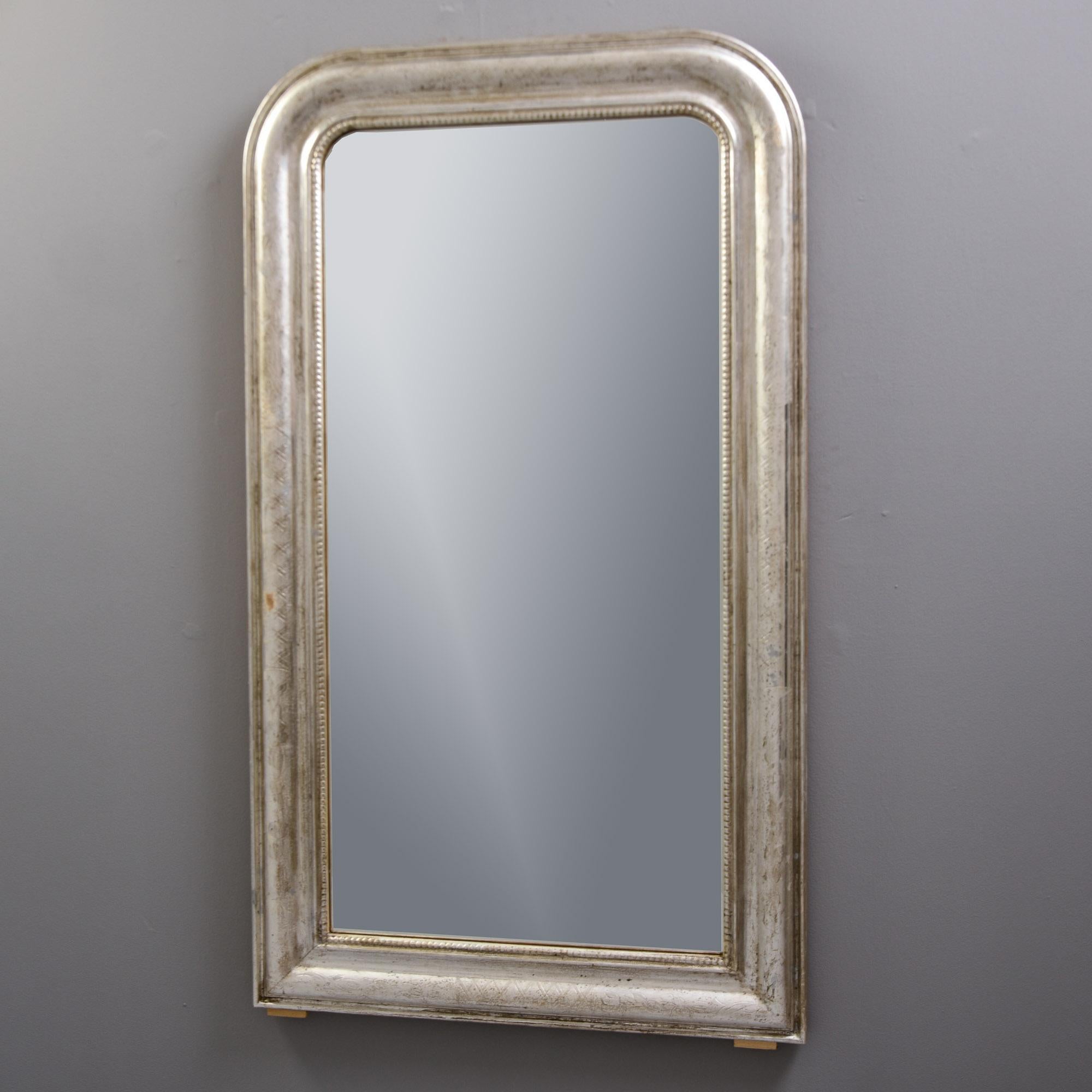 Found in France, this late 19th century silver gilt Louis Philippe mirror dates from about 1890. Just over four feet tall, the frame has subtle etched patterns of leaves, vines and X’s across the top surface and a beaded inner edge. Unknown maker.