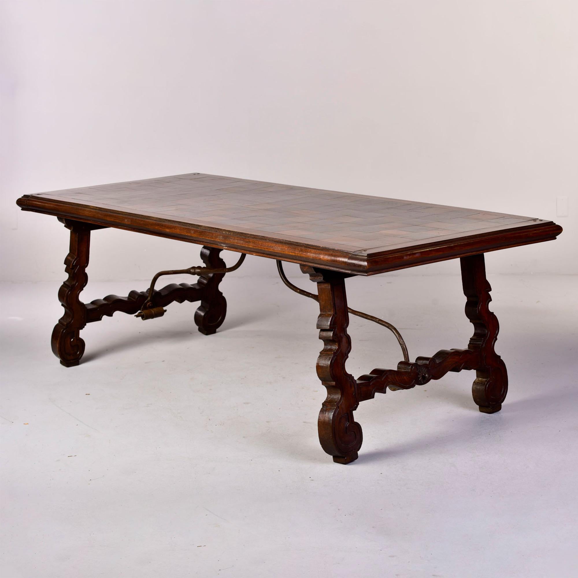 Circa 1840s large Spanish walnut table features marquetry work on the top, carved legs and an iron stretcher. Unknown maker. 

Apron height: 27.5”.
