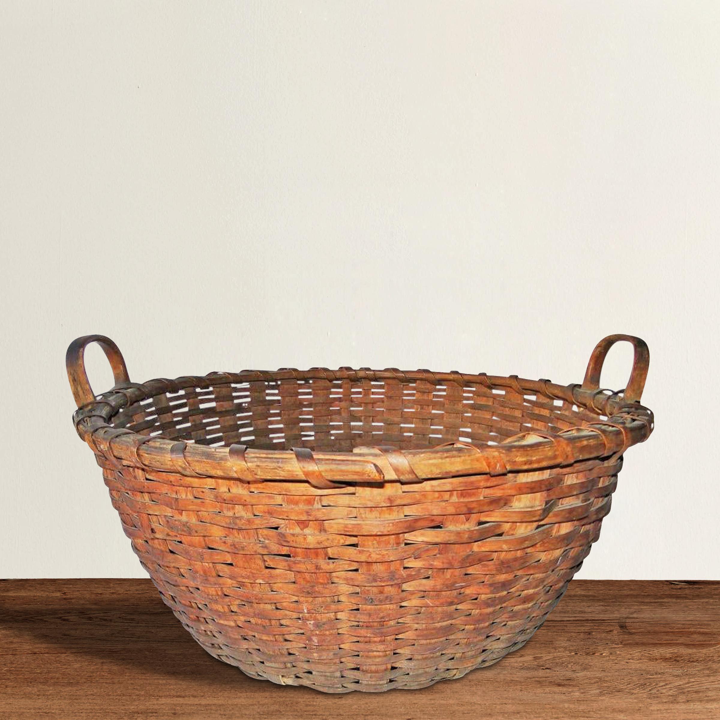 A large 19th century American handwoven ash splint cat head basket with a double -banded bentwood rim, carved and bentwood handles, and a fantastic patina only one hundred and fifty years of use can bestow. The term cat head refers to the shape of