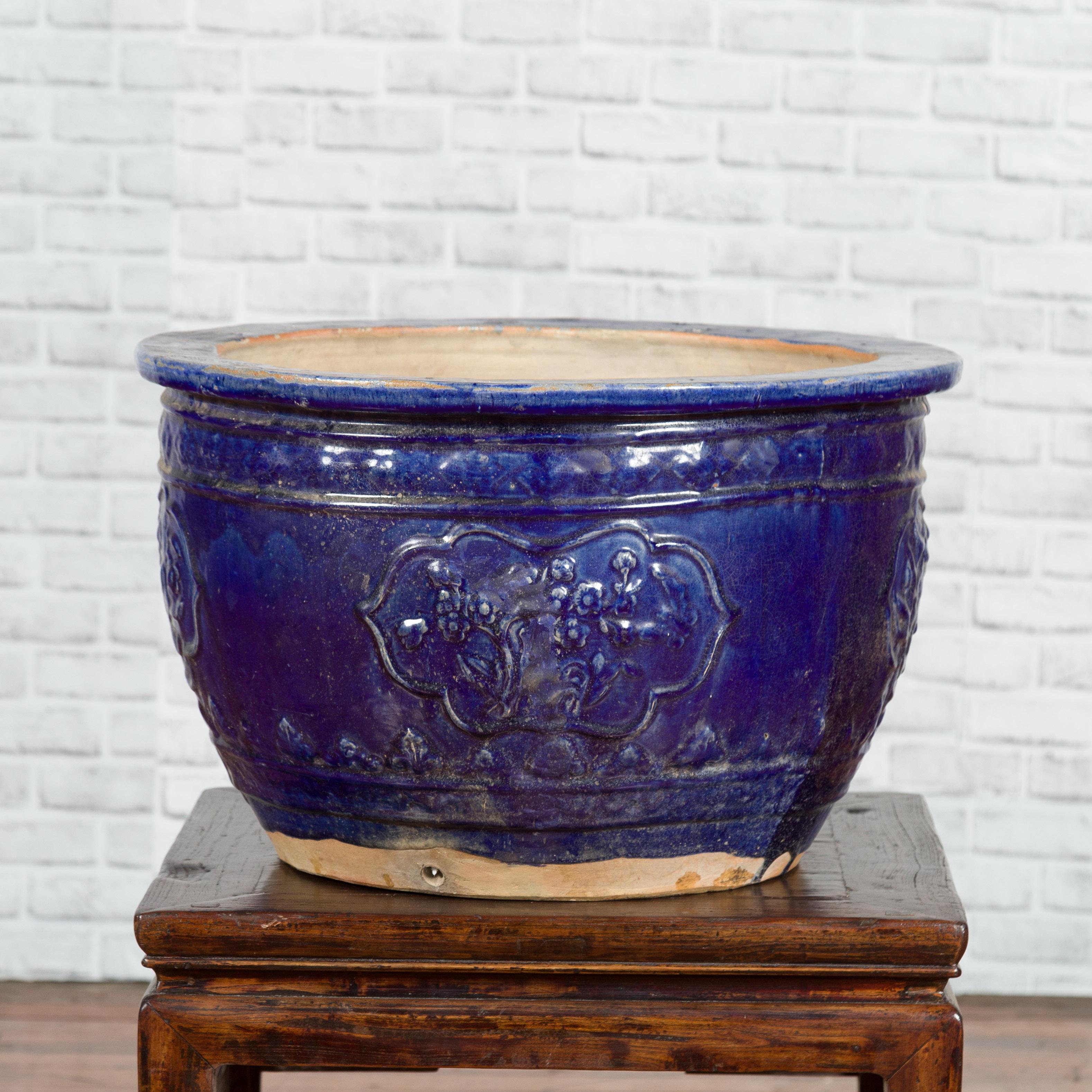 A large Vietnamese Annamese royal blue planter from the 19th century with floral décor. Handcrafted during the 19th century, this planter features a circular silhouette adorned with a royal blue glaze showing a nicely weathered appearance. Decorated