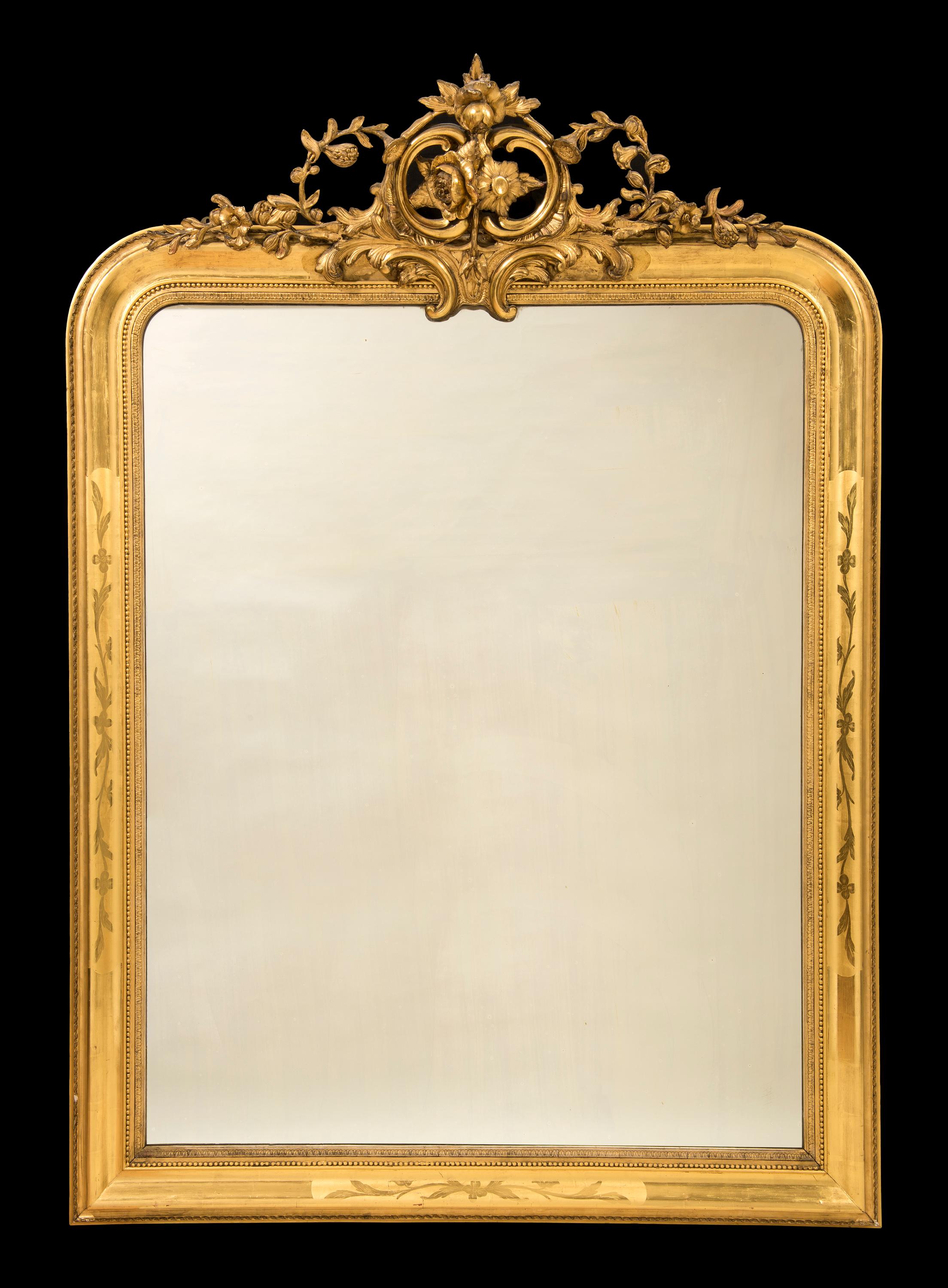 The large French wall mirror with crisply carved flowers and 'C' scrolls and etched flower decoration to the bevelled frame is surmounted around the original plate glass mirror.

Provenance
The Steve & Peg Hale collection.