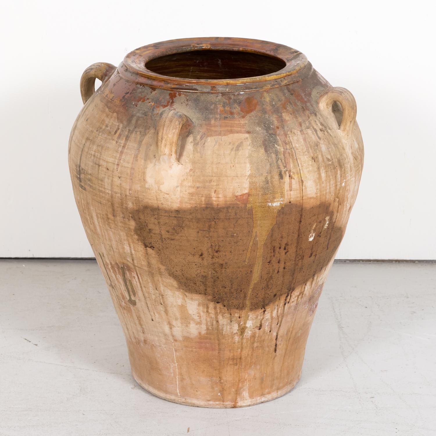 A large 19th century traditional Spanish terracotta orza or olive jar handmade in the province of Tarragona in Catalonia, circa 1890s, having four handles and an unglazed exterior with the neck, rim, and interior glazed. Used to preserve olive oil,