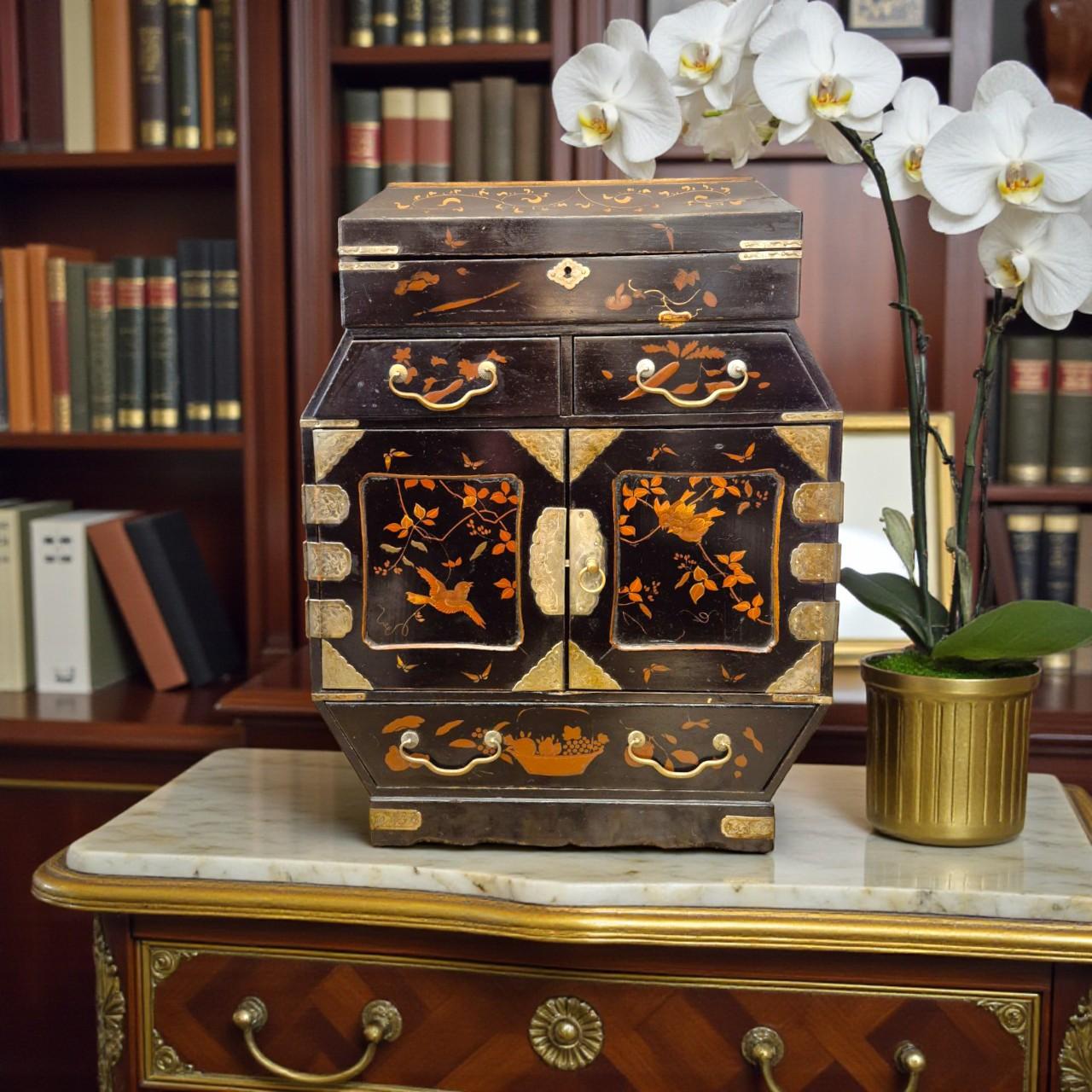 Refined and visually striking, this large 19th-century jewelry chest showcases exceptional craftsmanship and timeless decorative appeal. The piece is crafted in deep black lacquer and adorned with delicate gilt-painted floral and avian