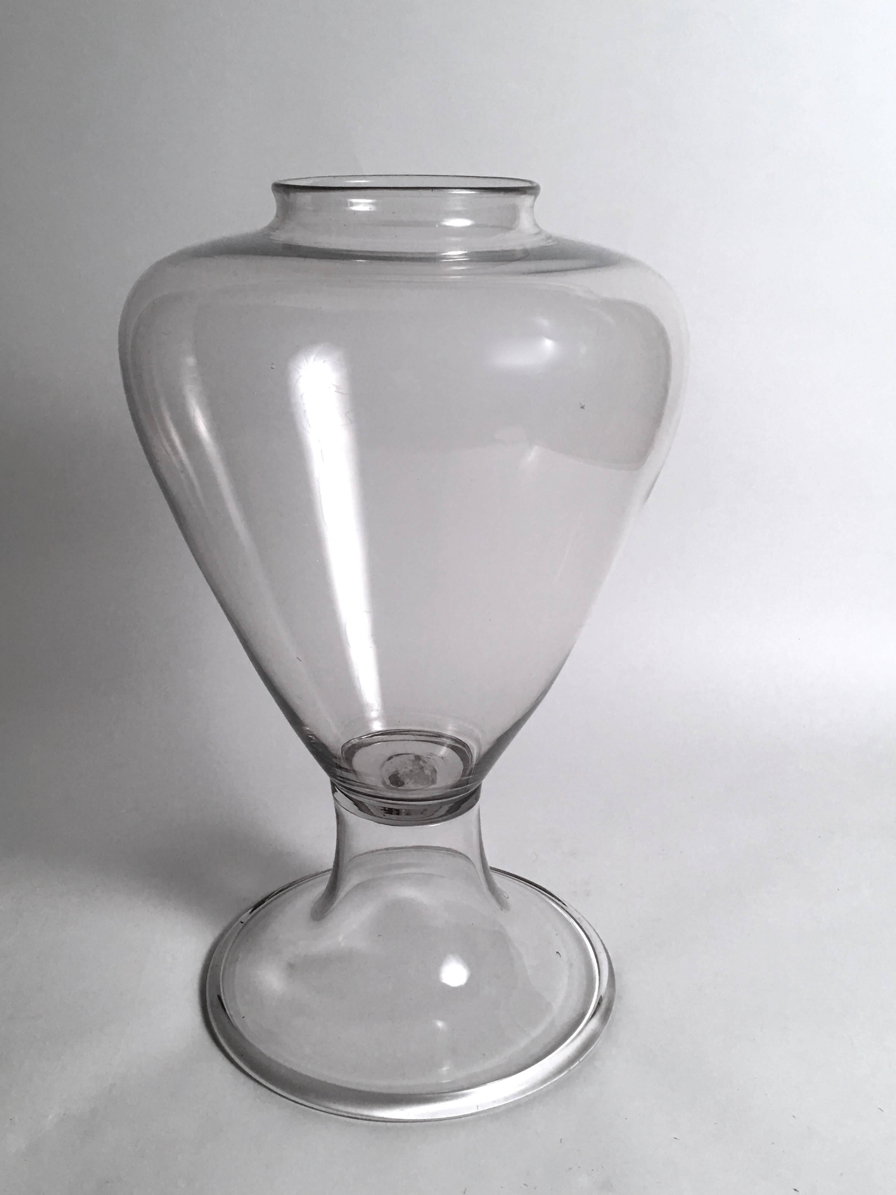 A large 19th century colorless blown glass apothecary jar, made in two sections, the top part with a circular opening over high shoulders tapering down to the spreading, trumpet form base with rolled edges. This unusual apothecary jar would be