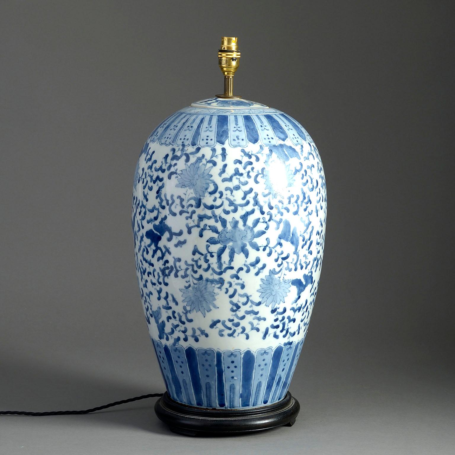 A large mid-nineteenth century blue and white glazed jar and cover, decorated throughout with flowers and foliage and now mounted as a lamp upon a turned ebonised base.

Wired to UK standards. This lamp can be re-wired to all international