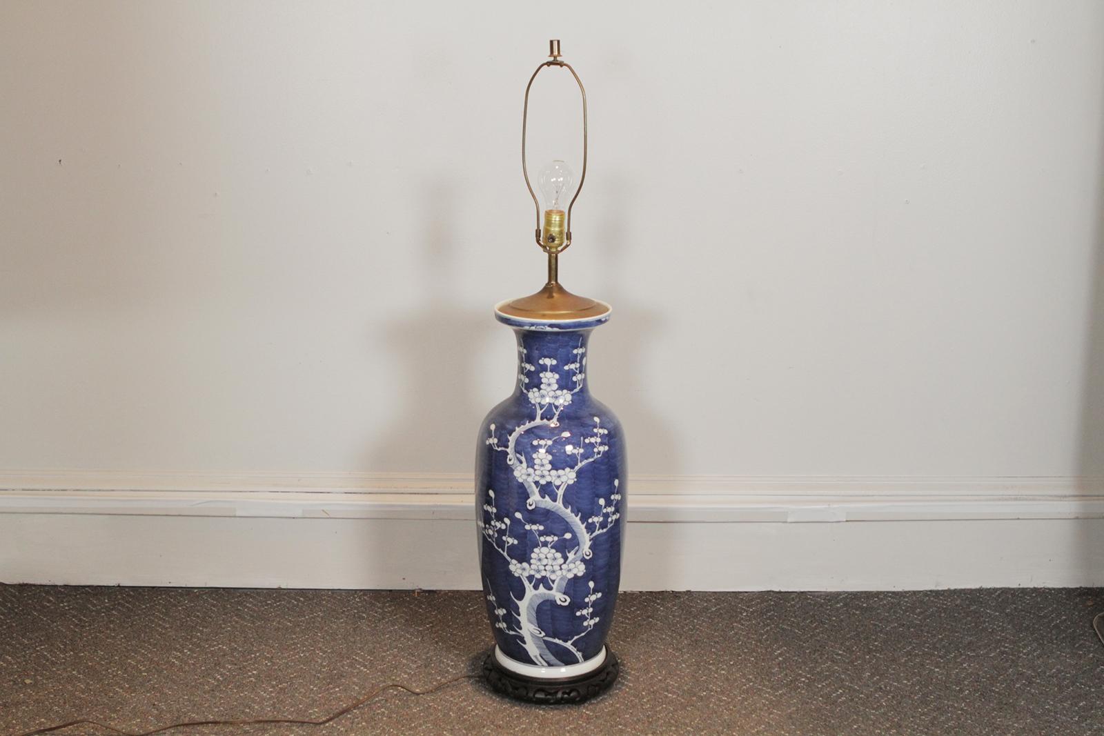 A 19th century blue and white cherry blossom porcelain vase now as a lamp. The vase with brass cap and carved wood base measuring 10' in diameter 32