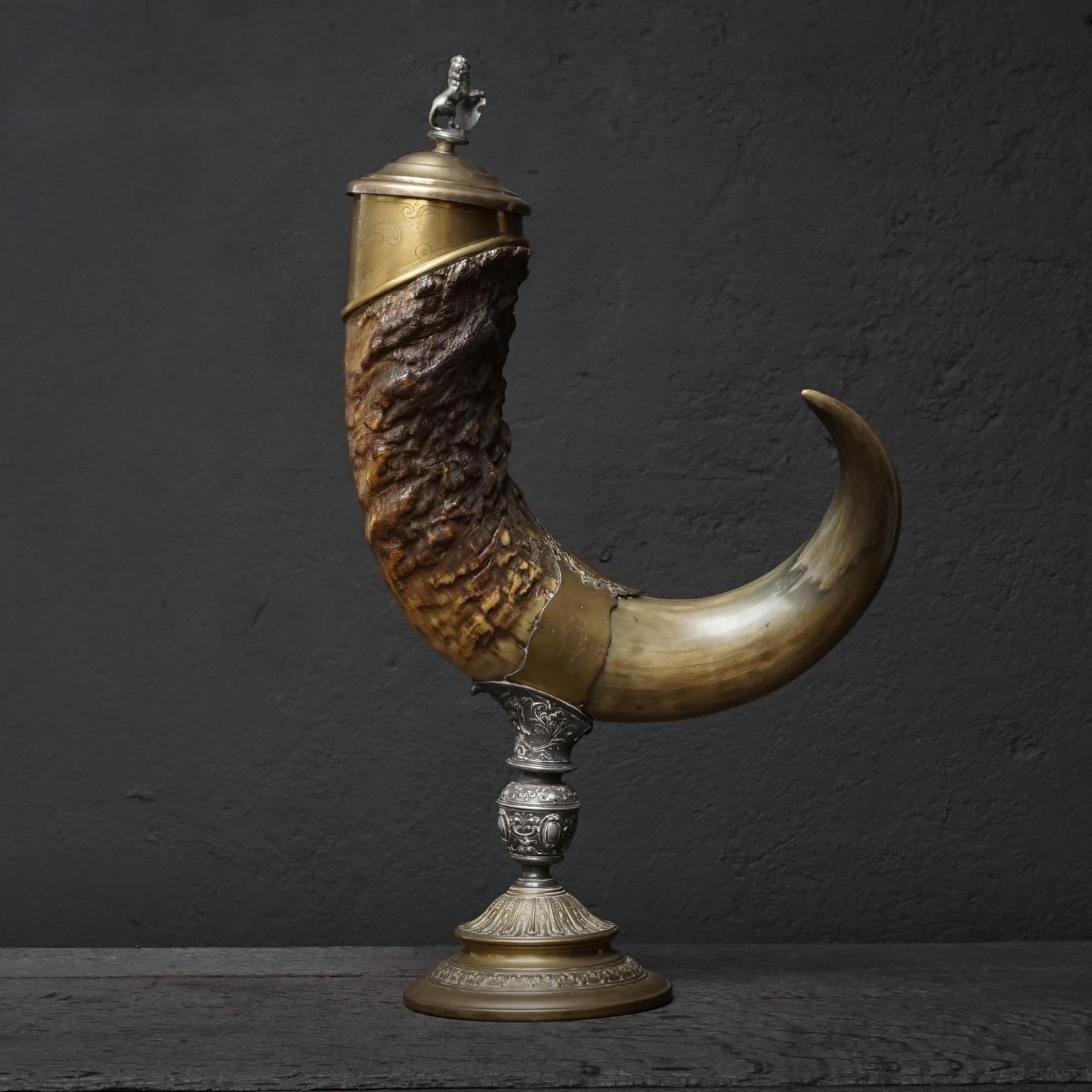 A very large drinking horn or 'Horn of plenty' made of Indian Water buffalo Horn, mounted in silver plated copper and metal, plated copper cover with on top a lion holding a coat of arms.
Very elaborated decorative engraving and embossing on the