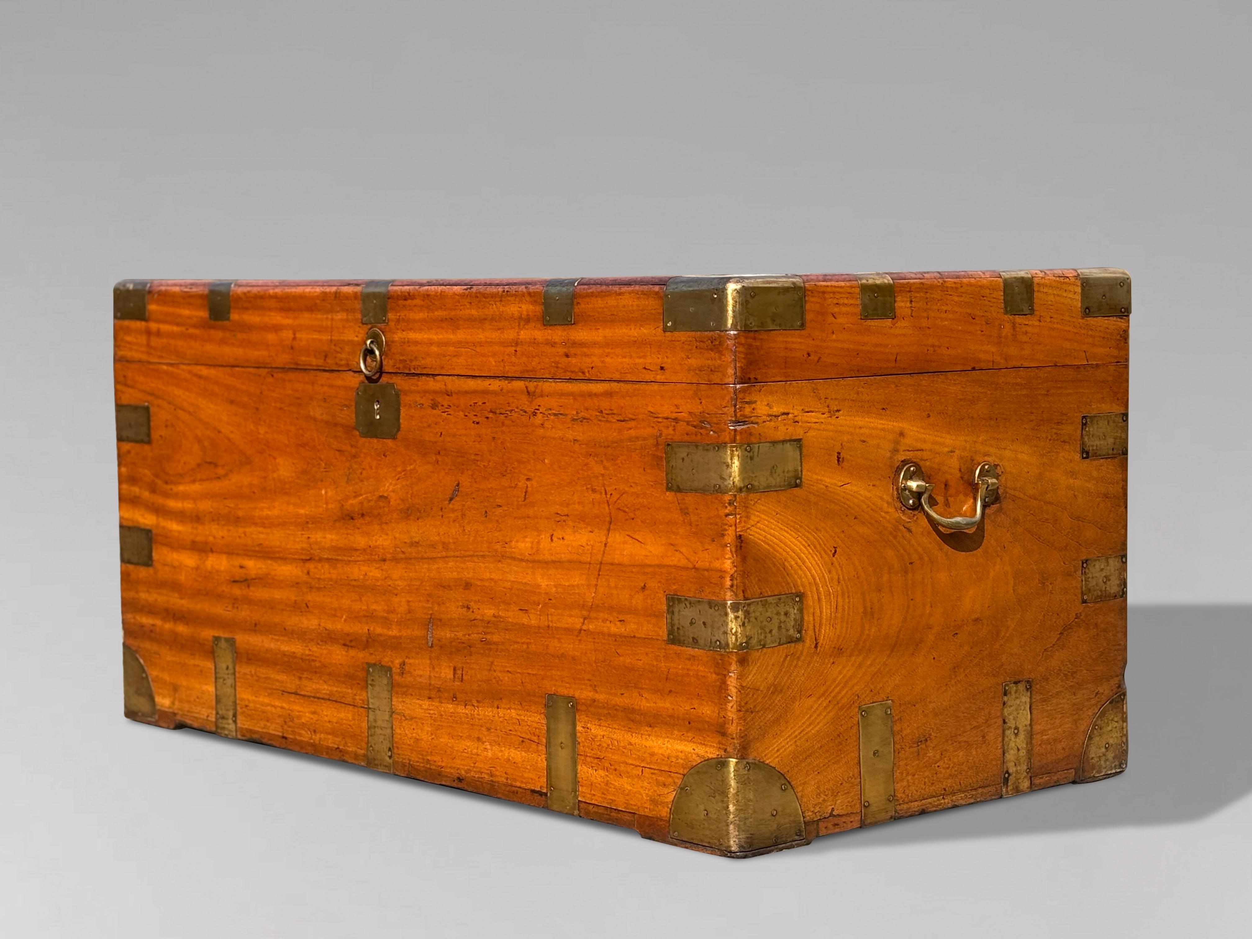 Un grande baule da viaggio in legno di canfora della fine del XIX secolo, rilegato in ottone e con maniglie in ottone. Presenta un colore e una patina caldi e ricchi, adatti all'uso come tavolino decorativo. I primi legni presentano un colore e una
