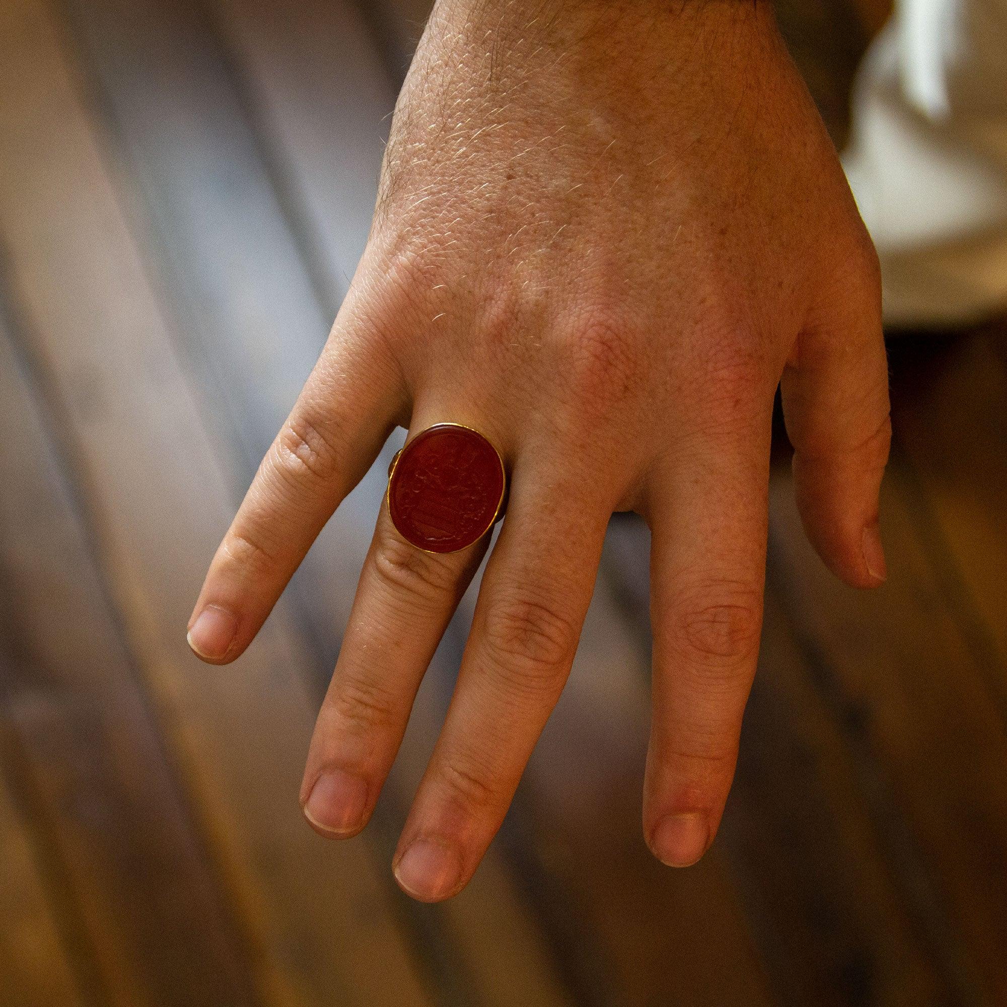 A large intaglio signet ring crafted from 18 karat yellow gold and set with an oval carved carnelian. The handmade ring would likely have been adapted from a 'fob' seal to a ring at same stage during the 20th Century, making it more wearable and