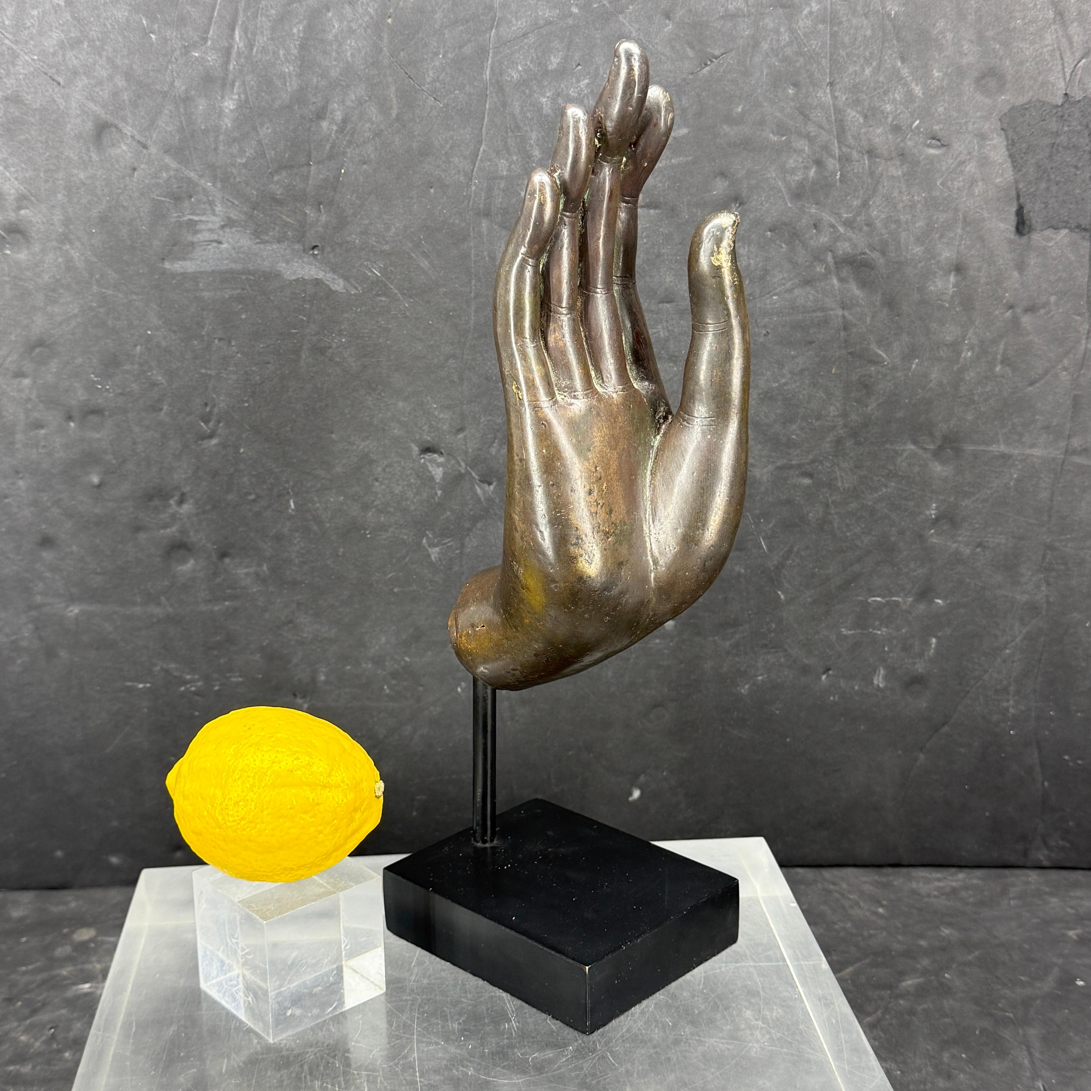 Impressionnante main de bouddha en bronze moulé sur une base en acier noir. 
Abhaya Mudra : Geste de réconfort, de bénédiction et de protection. Ne craignez rien.
Elle serait merveilleusement exposée sur une console ou une table basse, ainsi que sur