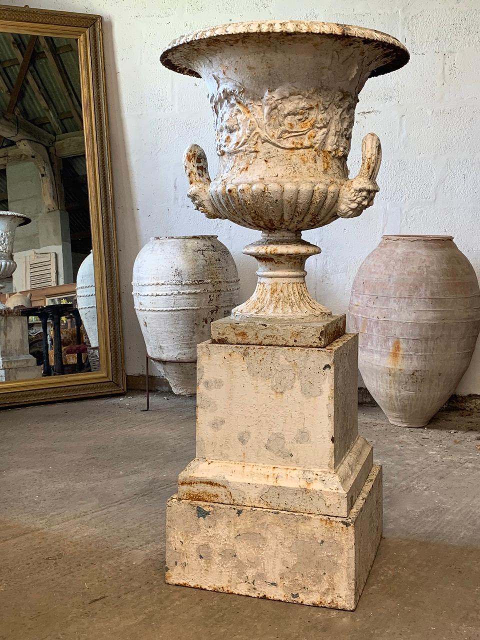 An impressive 19th century double handled cast iron urn by the Handyside Foundry. Standing on its original iron plinth which is in 2 parts. It is a good size and will make a nice center piece in the garden. With nice old weathered paint which adds