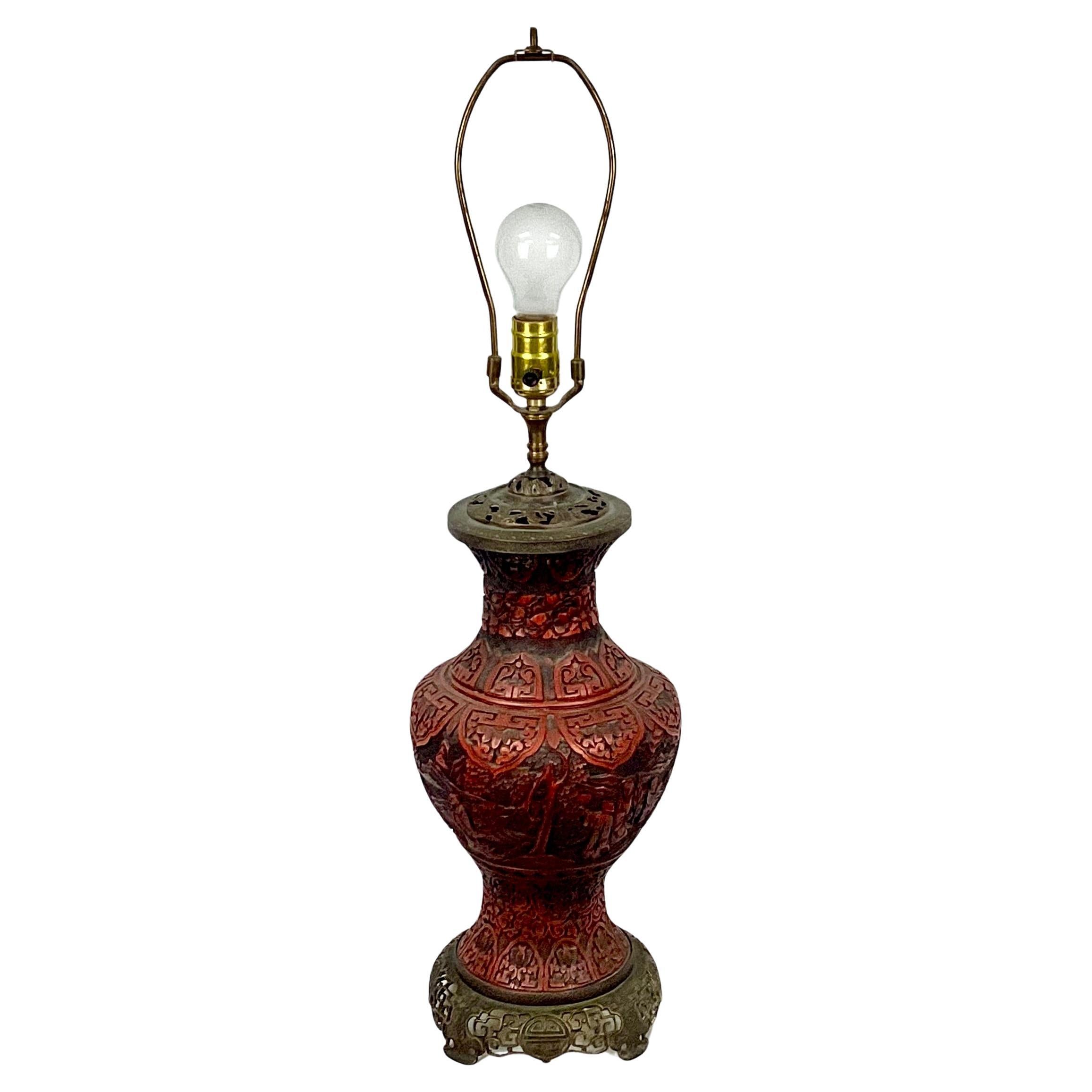 Il s'agit d'un superbe vase-lampe en laque de cinabre chinois du 19e siècle. La lampe présente des scènes sculptées de savants dans un paysage avec des feuillages en cinabre, ainsi que des détails complexes en laiton sur le dessus et la base. La