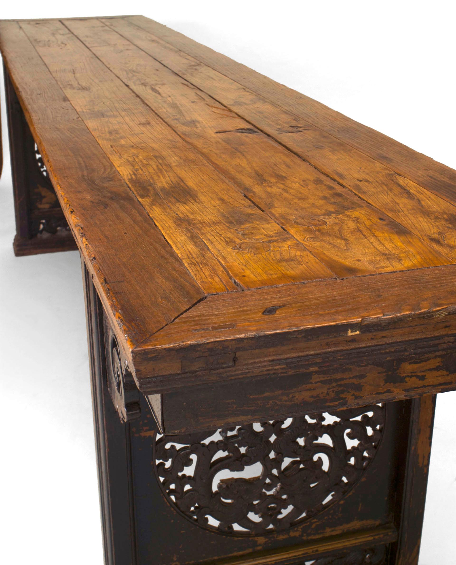 19th century Chinese hardwood altar table with a plank top supported  by side pedestals, each carved with a circular filigree cutout beneath a double scroll design apron.