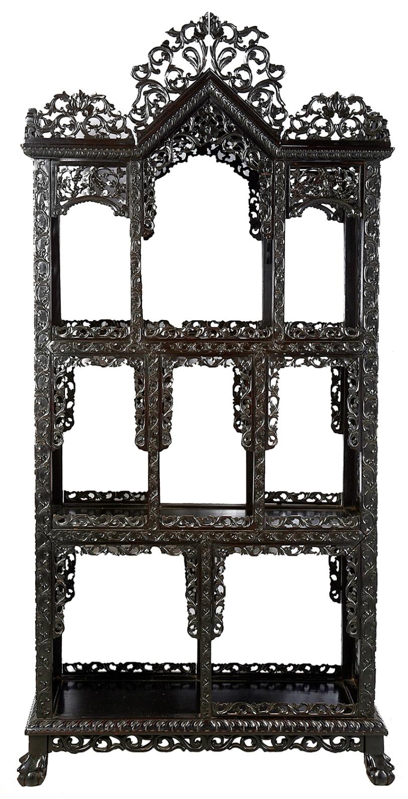 A good quality set of 19th century Chinese hardwood shelves, having an architectural pediment with fine carved and fretted scrolling foliate, egg and dart molding, three tiers of shelving each with carved fretwork panels to the sides and raised on