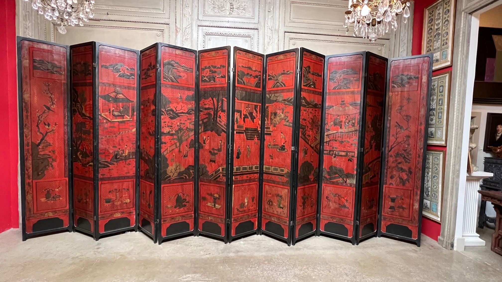 A very large and beautiful Chinese Coromandal 12 panel folding screen with an overal etched and carved surface of fretwork court scenes, animals and flowers. 
This screen is in a wonderful Chinese red with black lacquer framing. It is finished